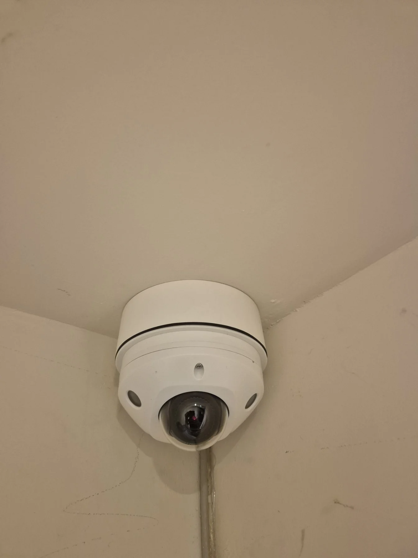 A security camera mounted on a ceiling corner in a room.