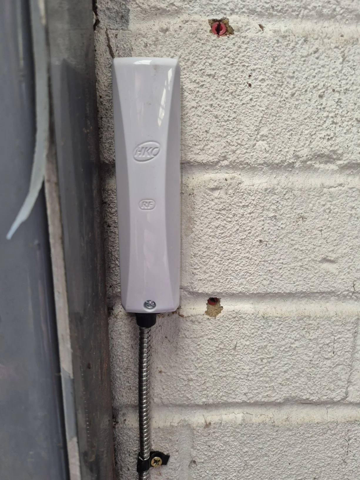 Close-up of an outdoor telephone or intercom device mounted on a beige brick wall.
