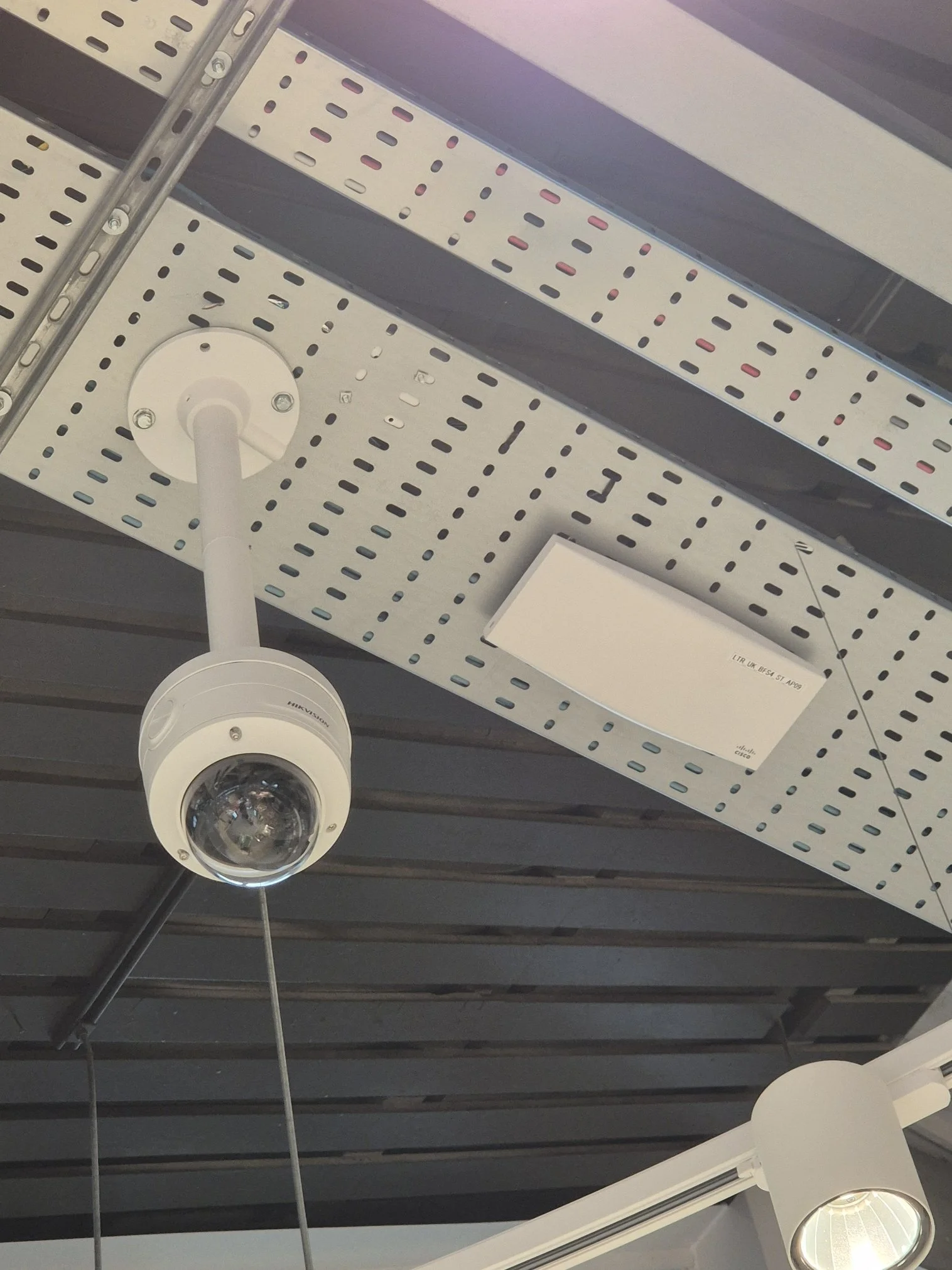 Ceiling-mounted security camera and LED light fixtures in an industrial or commercial space.