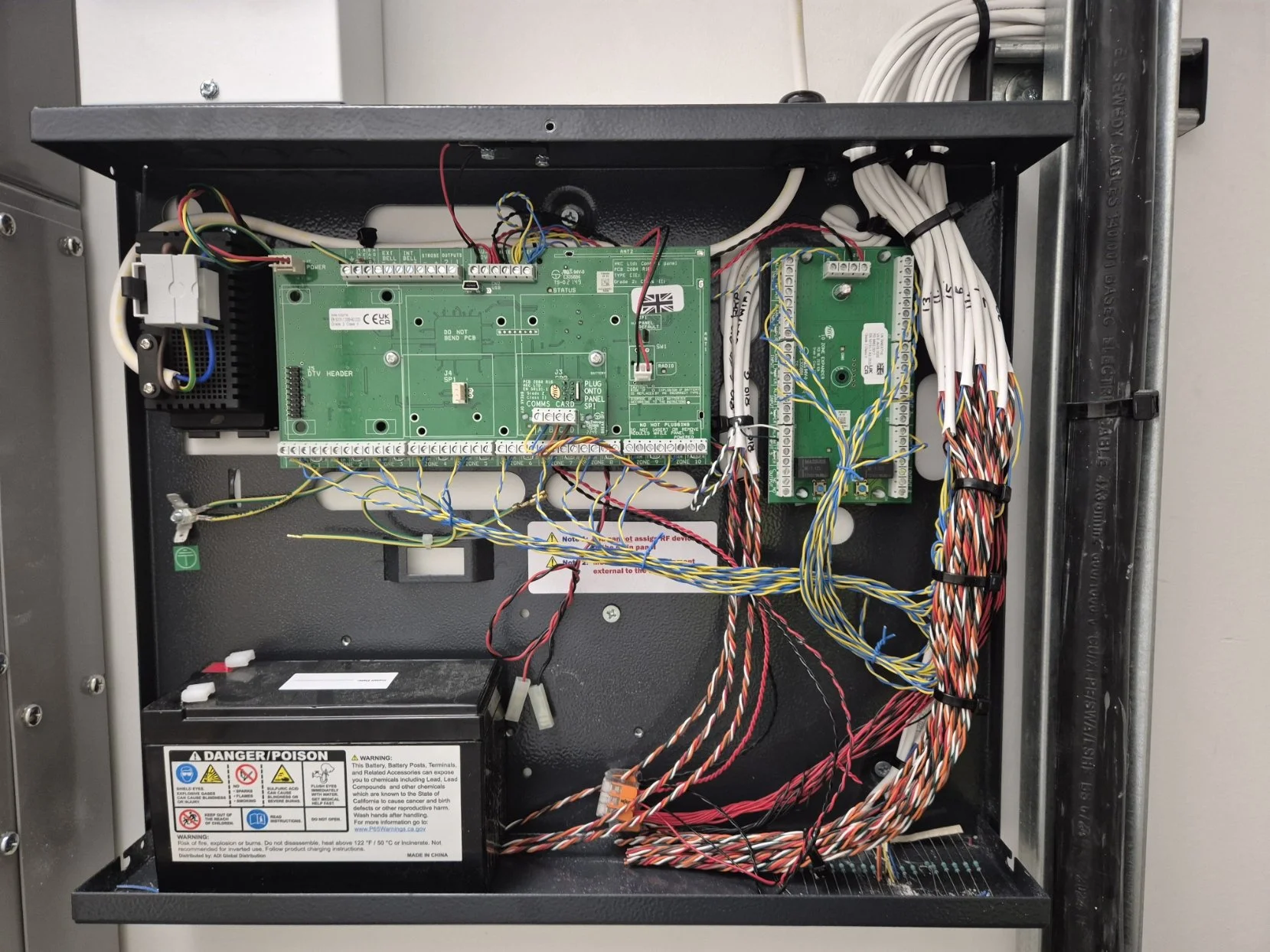 Inside an electronic control panel with circuit boards, power supply, and various wires connected.