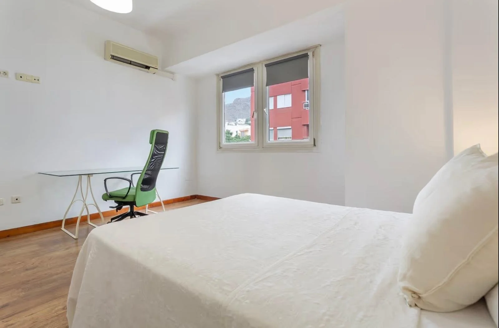 Habitación sencilla con cama, ventana y escritorio con silla