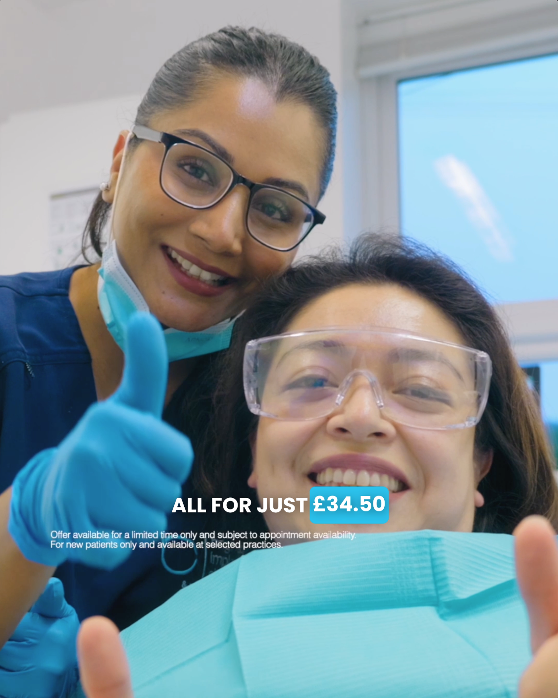 Two smiling dental professionals, one wearing glasses and the other wearing goggles, pose with thumbs up inside a dental clinic.