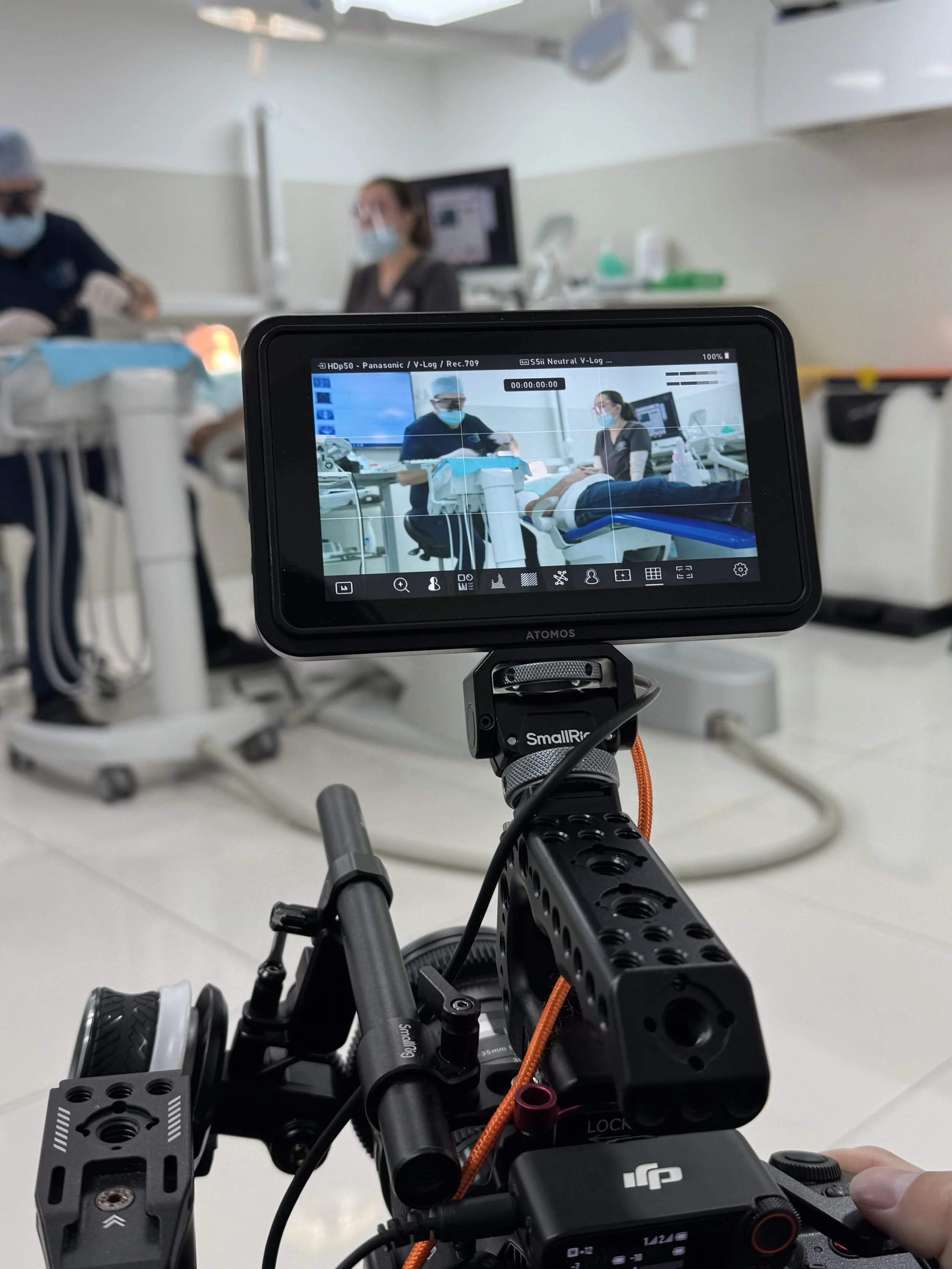 Filming a medical procedure in a hospital setting with healthcare professionals wearing masks.