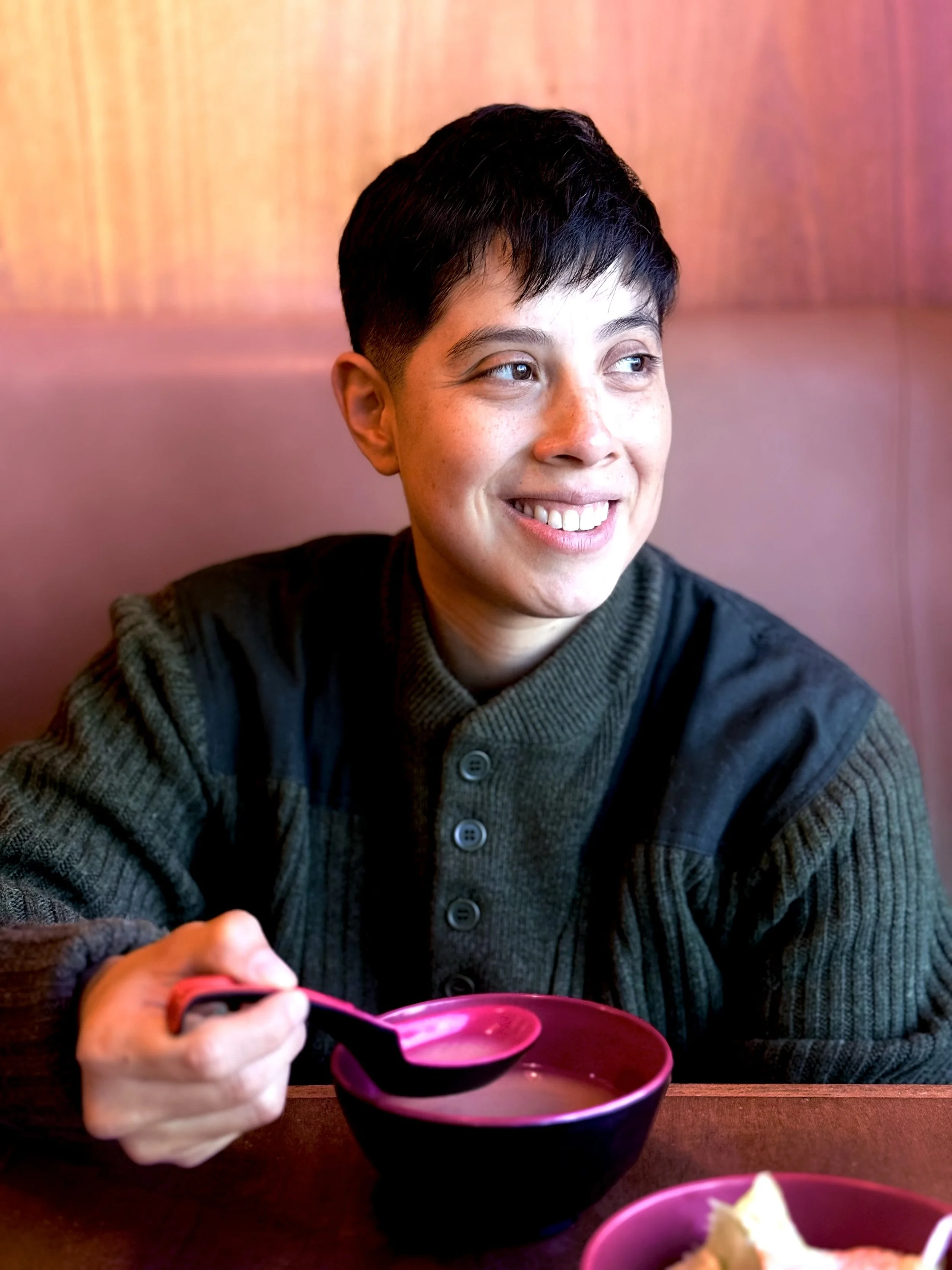 A smiling woman with short dark hair, glasses, and a black top.