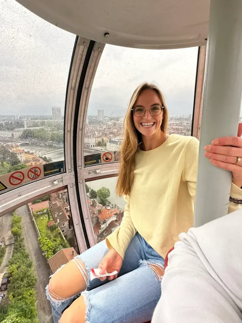 Addy Allen, licensed EMDR therapist in Largo, Florida and San Antonio, Texas, smiling inside a glass observation tower with a panoramic city view - reflecting perspective and growth through trauma therapy and anxiety therapy.
