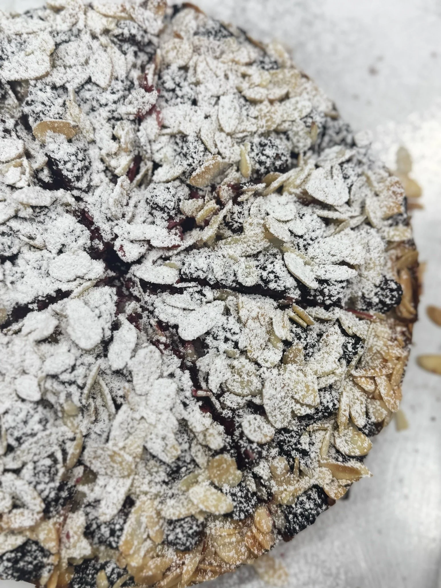 Close-up of sliced blackberries topped with almond slices and powdered sugar.