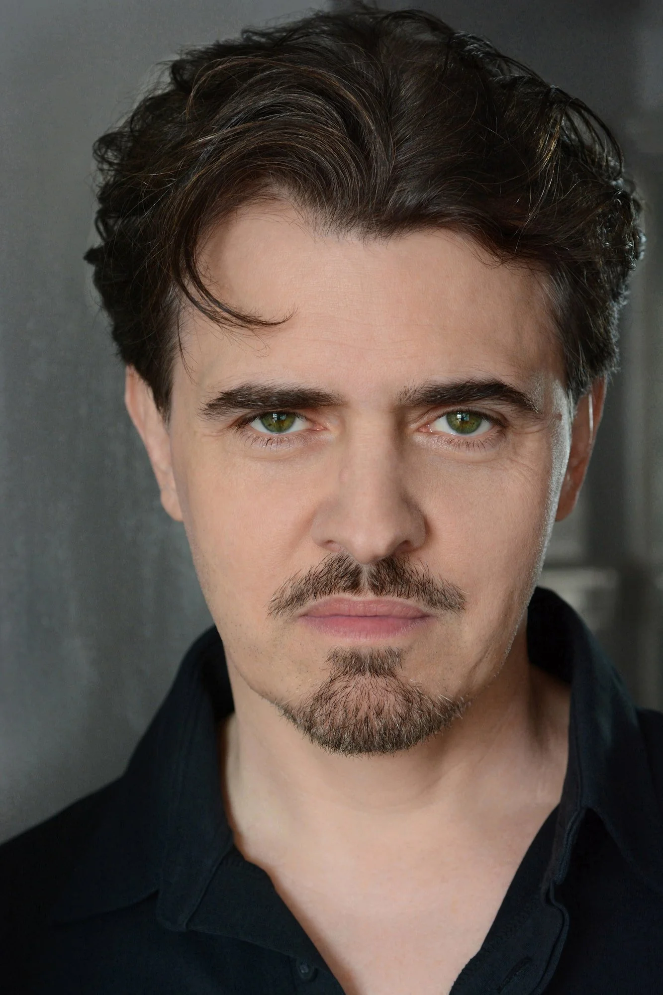 Jason Arcaro headshot, direct gaze, Van Dyke beard, black Henley shirt