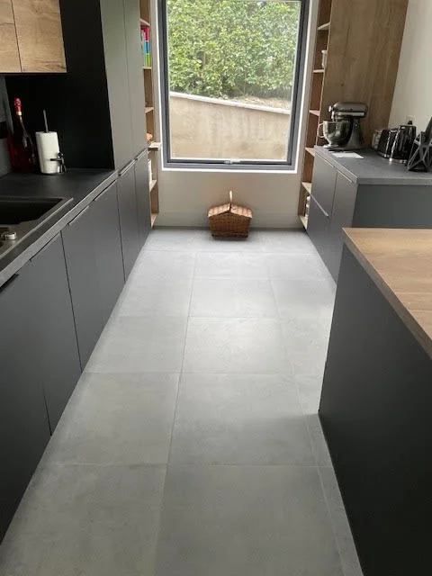 Kitchen with gray cabinets, toaster, mixer, and a window at the end with a basket underneath