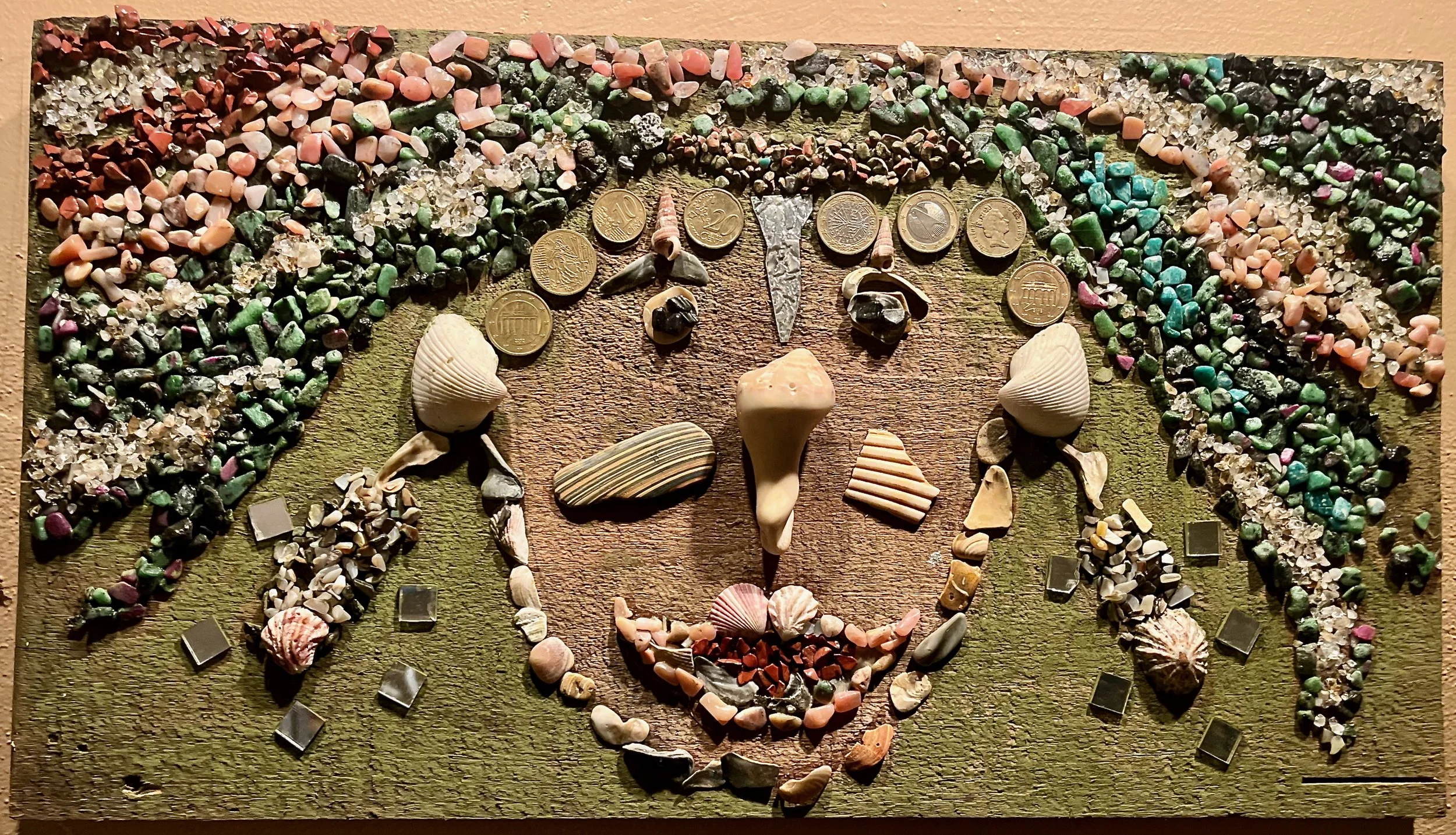 "Mer-Woman" 2021, shells, coins, stone, glass on wood, 20.5" x 11.25"