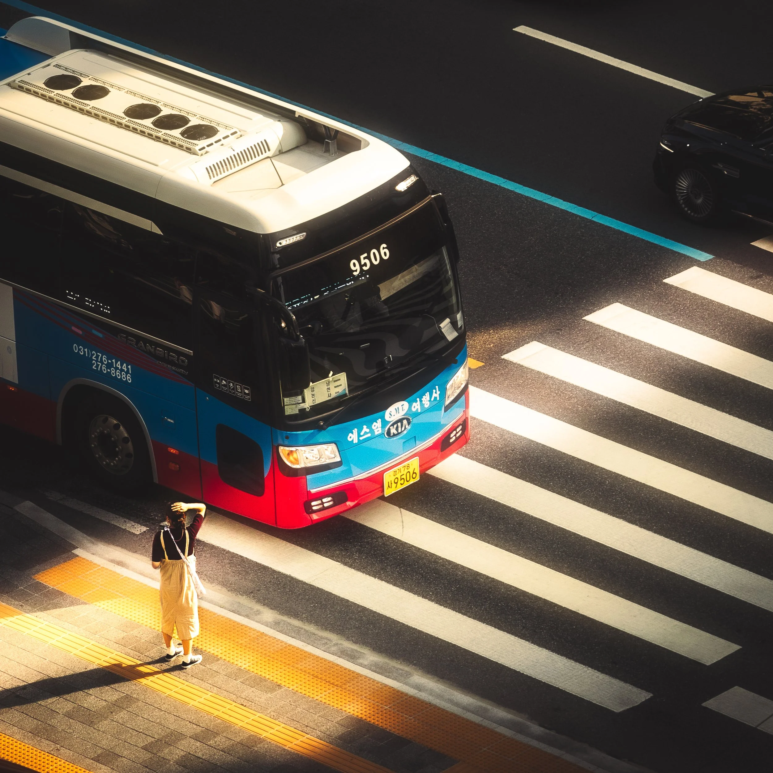 A woman shields her eyes from the sun as she waits at a crosswalk in Seoul, South Korea.