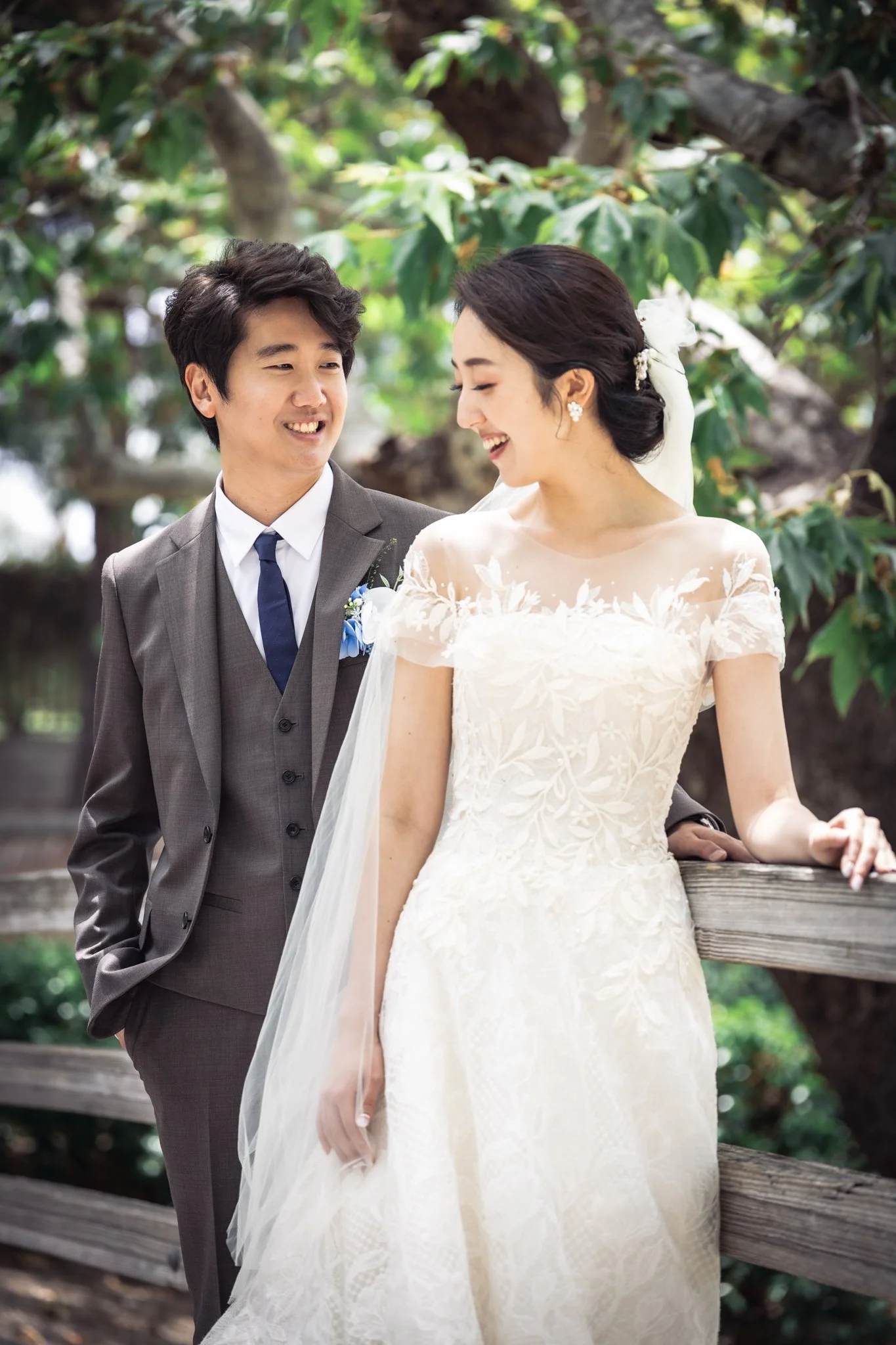 Groom smiles at his bride under a canopy of leaves.