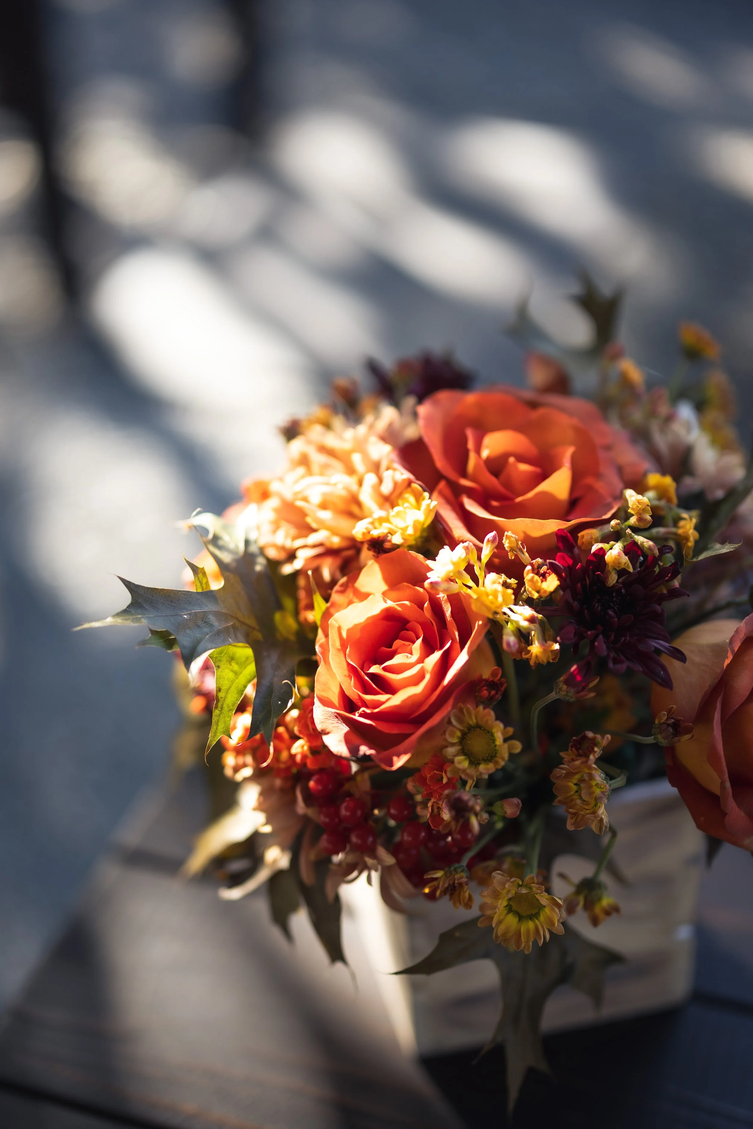 Orange, peach, yellow flowers as table decor at a wedding.