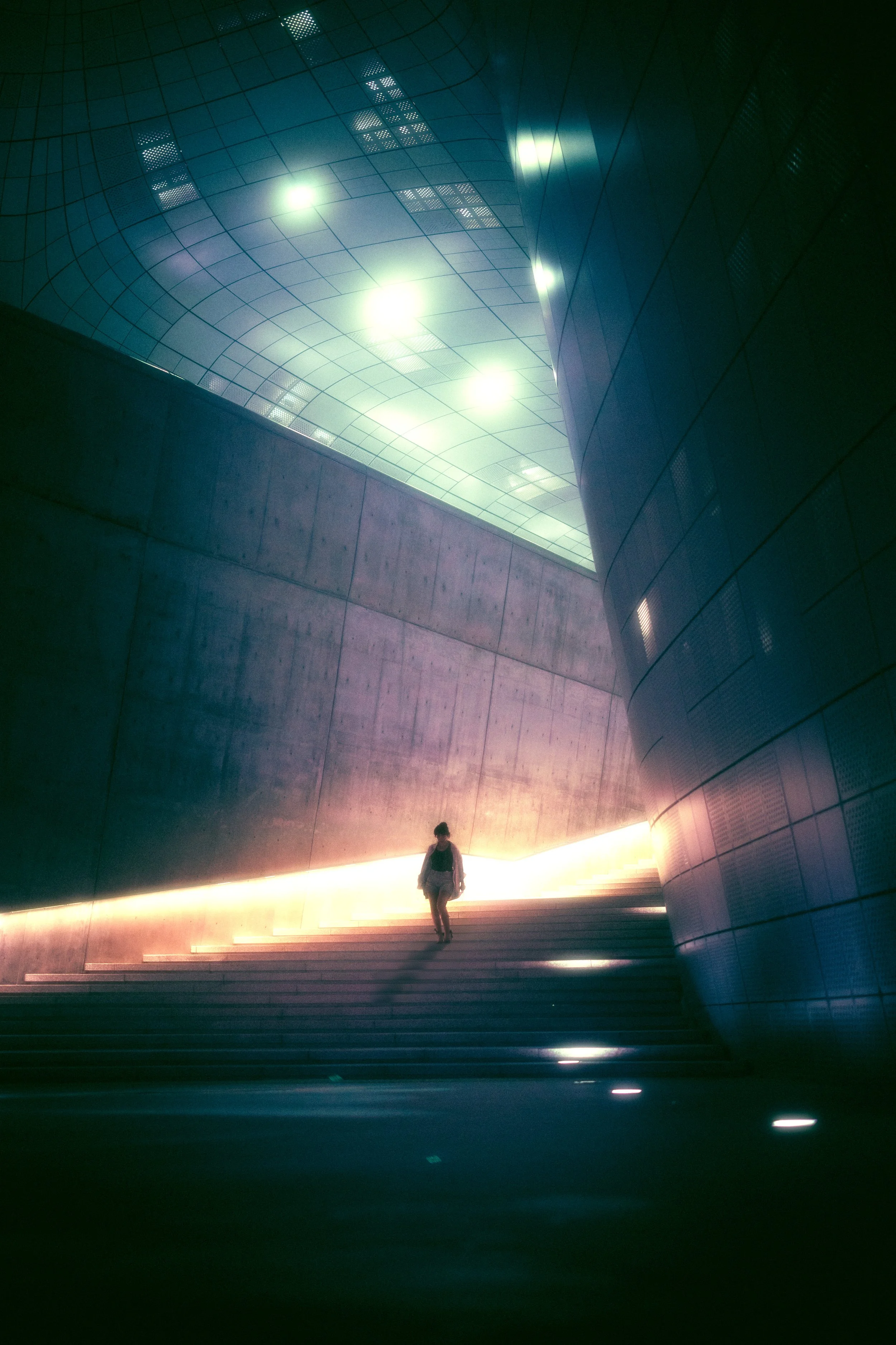 A silhouetted figure walks down the stairs at a cyberpunk-esque Dongdaemun Design Plaza (DDP) in Seoul, South Korea.
