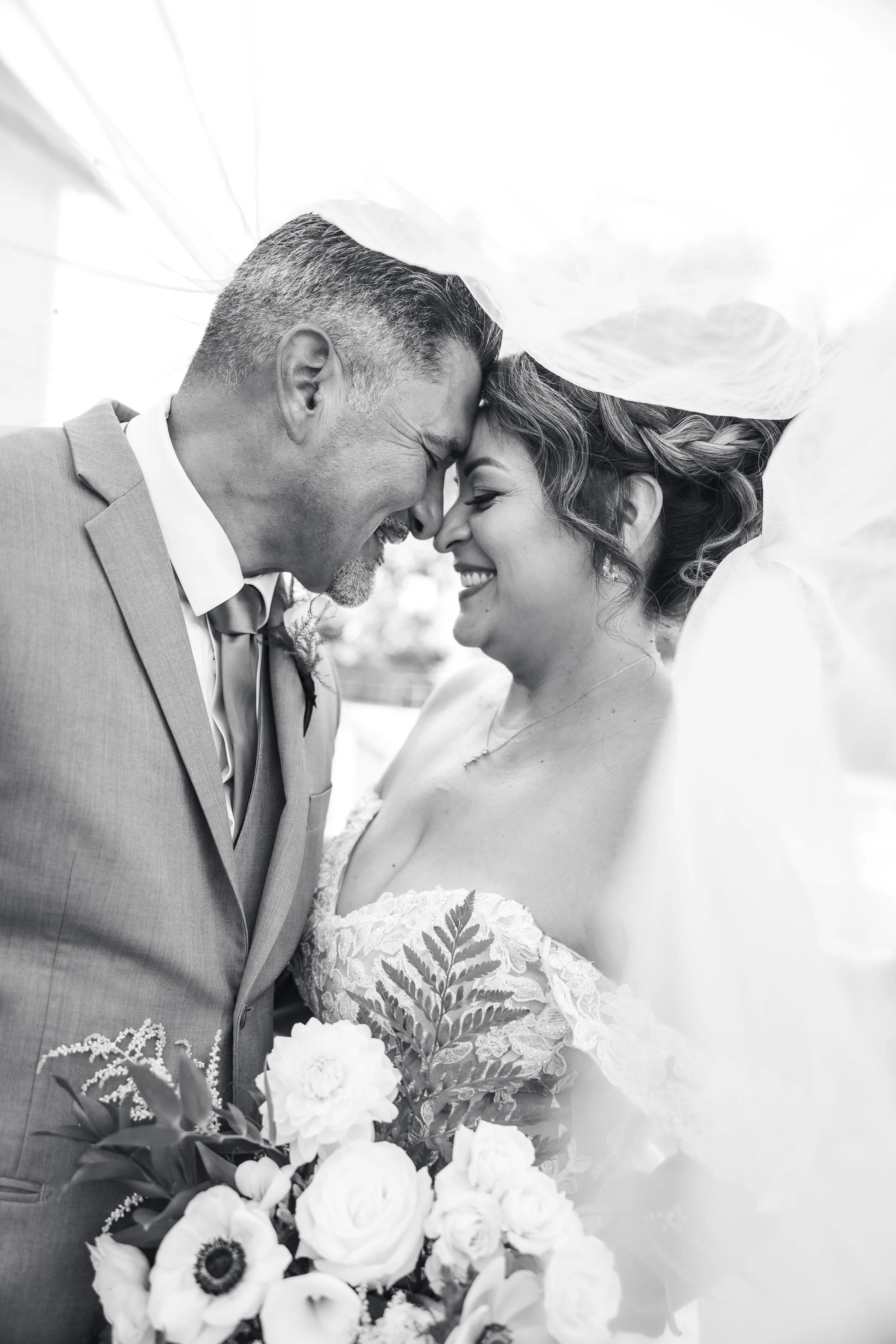 Bride & groom smile at each other under bride's veil