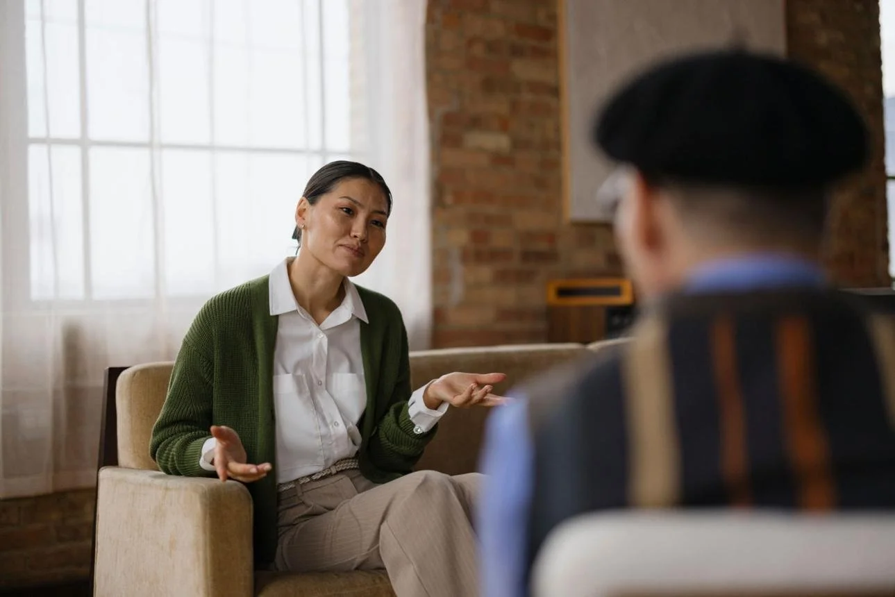 Therapist speaking with a client during an in-person therapy session in a calm, well-lit office