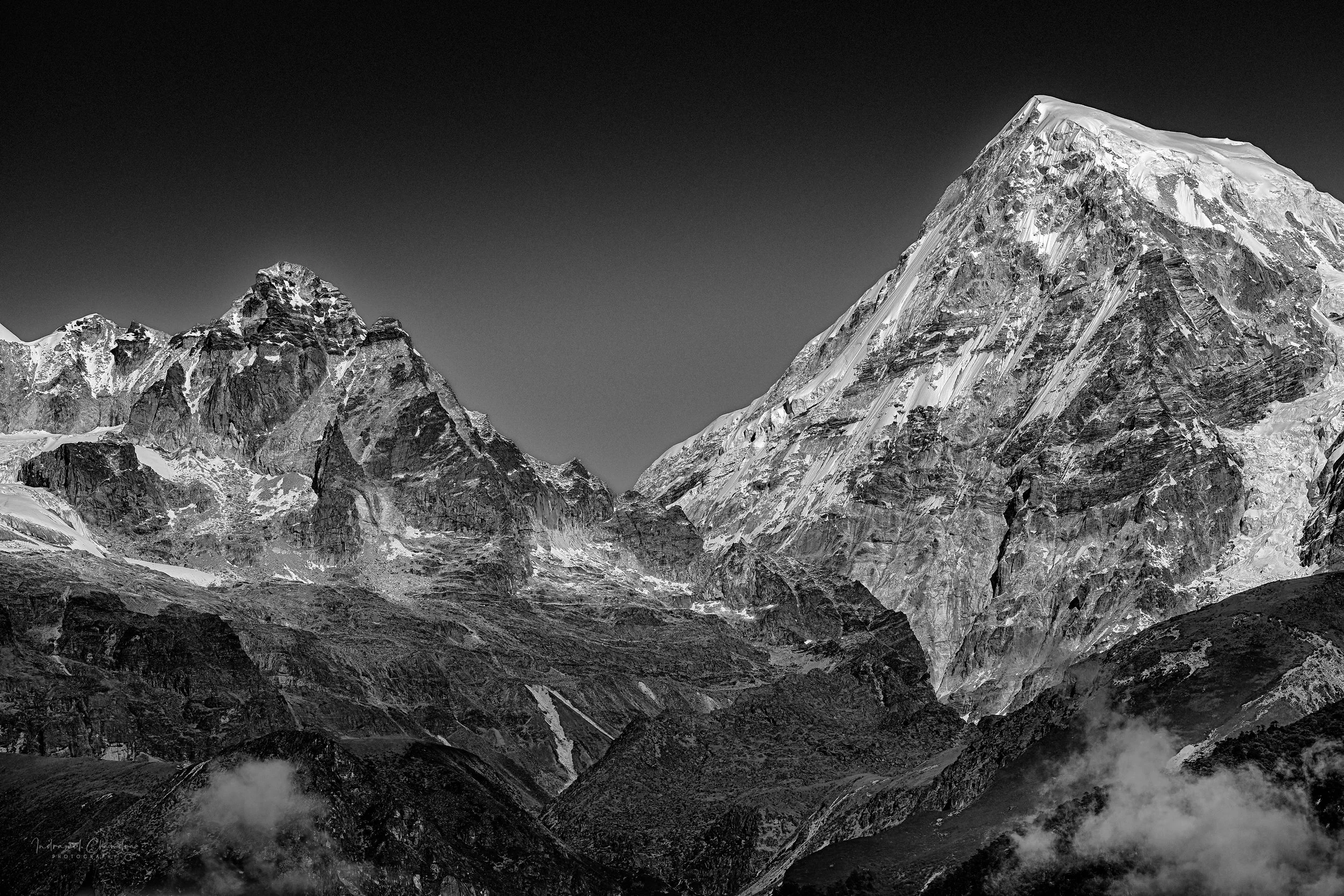 The rugged peak of Mt. Rathong rises sharply within the Kanchenjunga Massif, its icy face catching the first light of day in the high Eastern Himalayas.