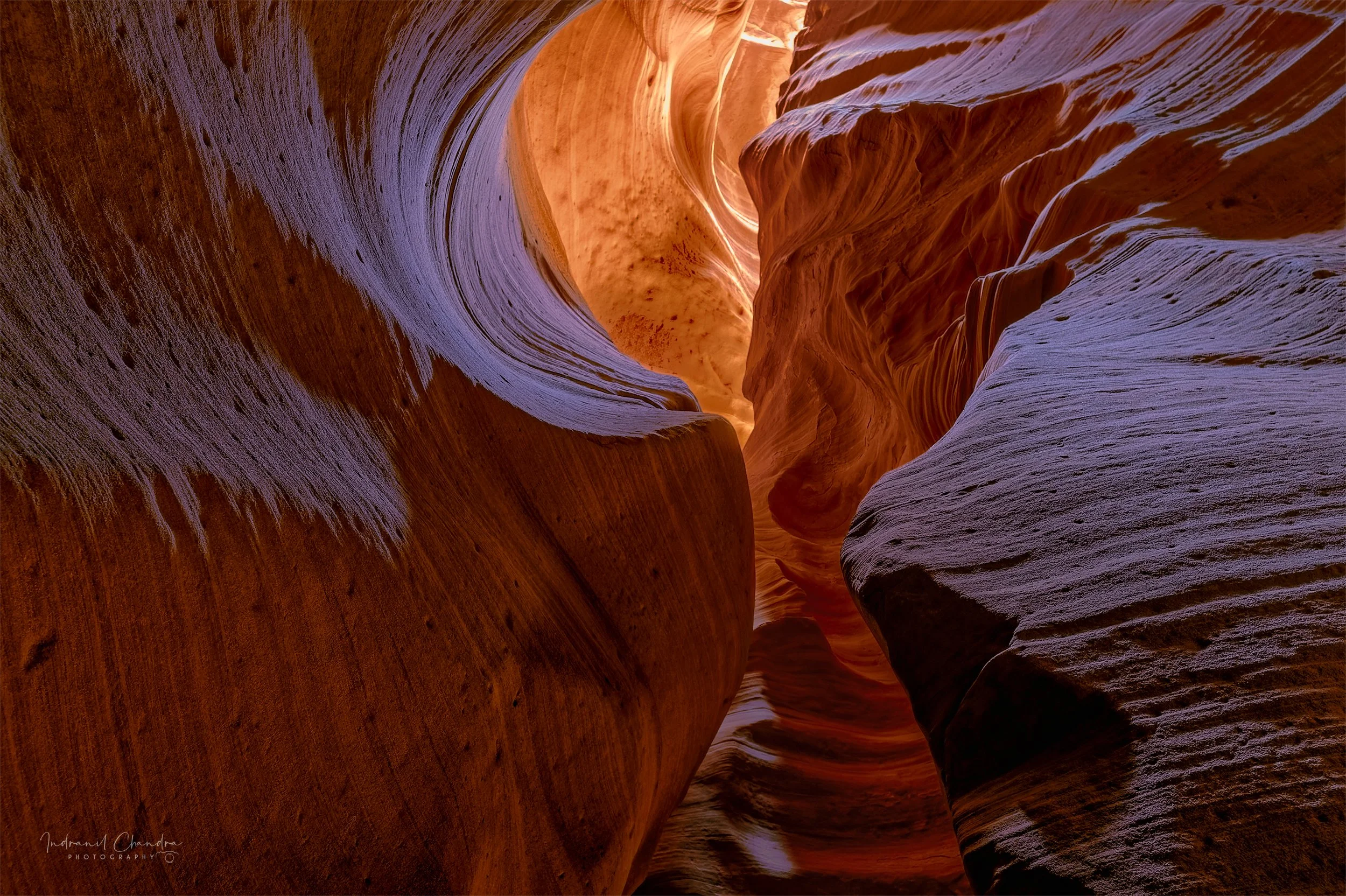 Canyon X, mid-morning, flat on my back on the canyon floor looking straight up. The camera saw more than my eye did: over a thirty-second exposure, light bouncing between the walls accumulated into the violets that sit against the fired orange above.