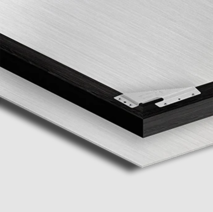 Close-up of the corner of a modern, minimalist desktop with a metallic frame and black edge.
