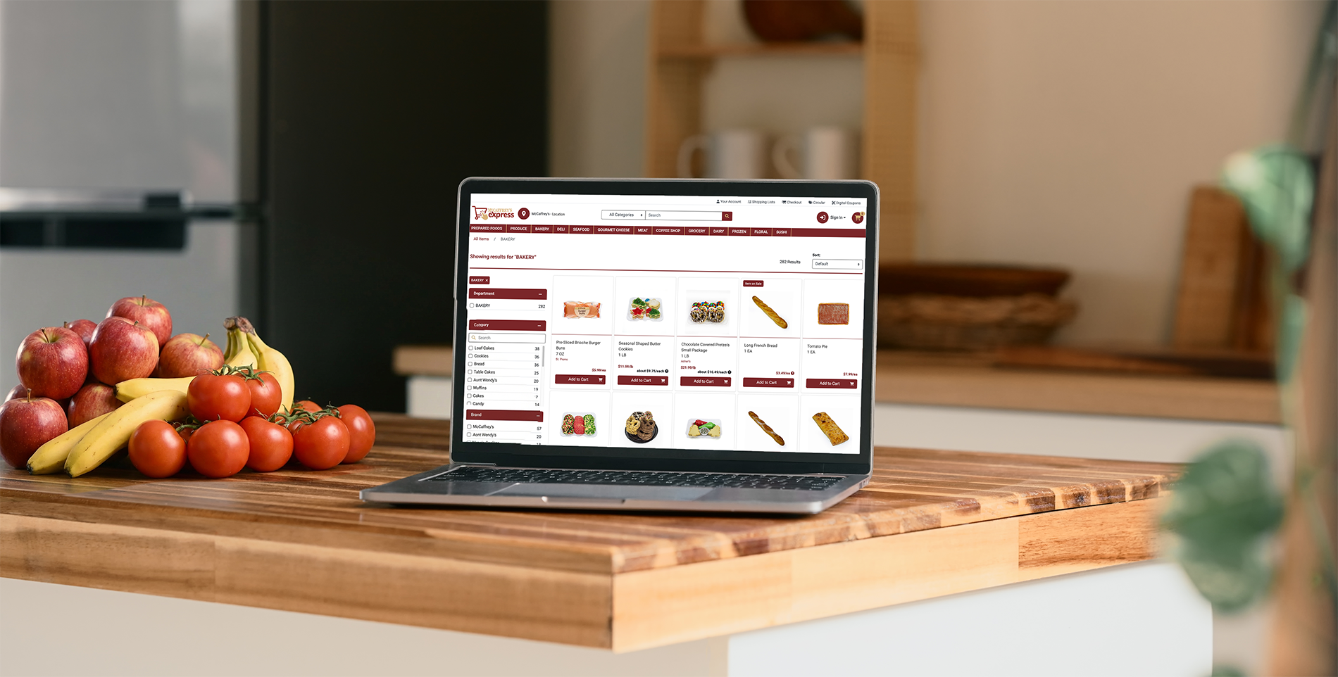 Laptop on wooden kitchen counter showing the McCaffrey's Express bakery shopping page
