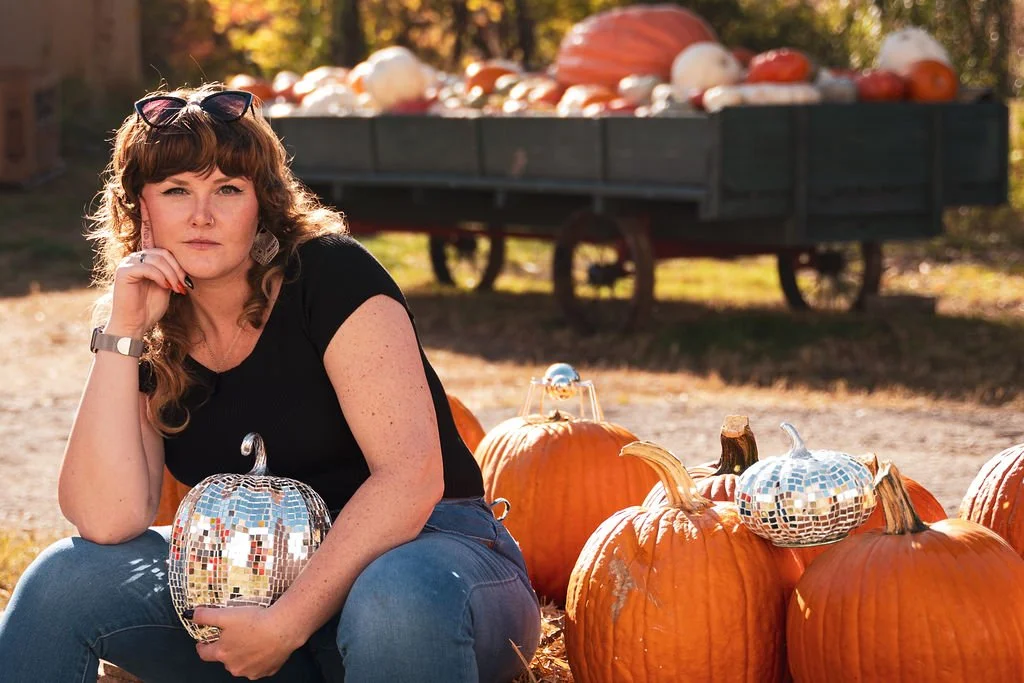Felicia holding disco pumpkin sitting like thinking man