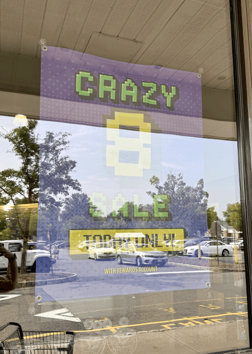 Photo of window banner with reflection of McCaffrey's crazy 8 sale in-store