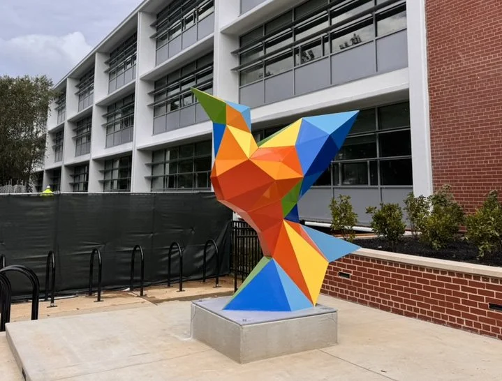 SOAR, a colorful geometric steel bird sculpture in orange, yellow, blue, and green, installed in front of J.O. Wilson Elementary School in Washington, DC.