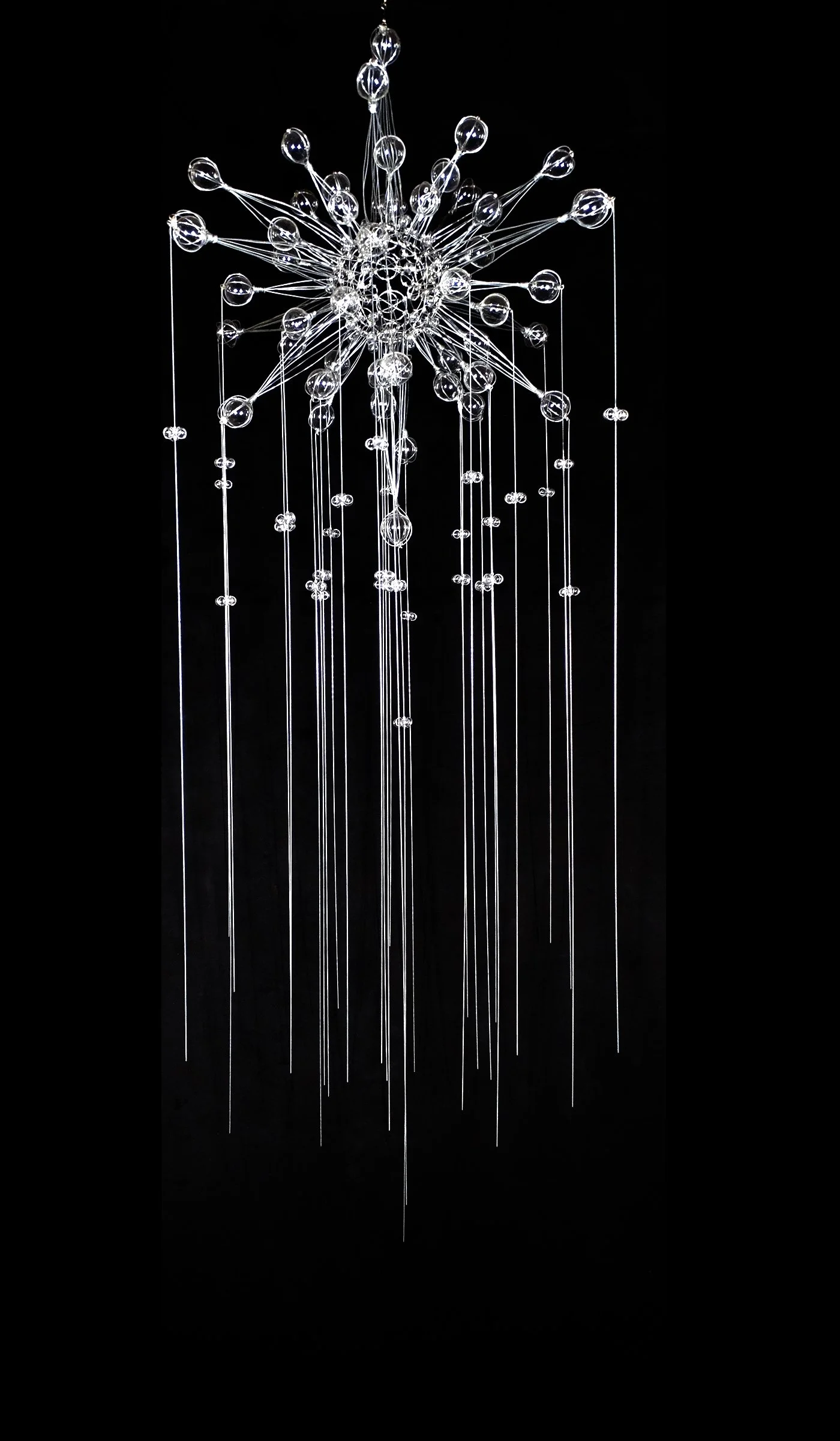 Lunar Sunshine, a suspended steel-wire and glass sculpture, radiates from a dense central cluster into delicate vertical strands and clear glass orbs.