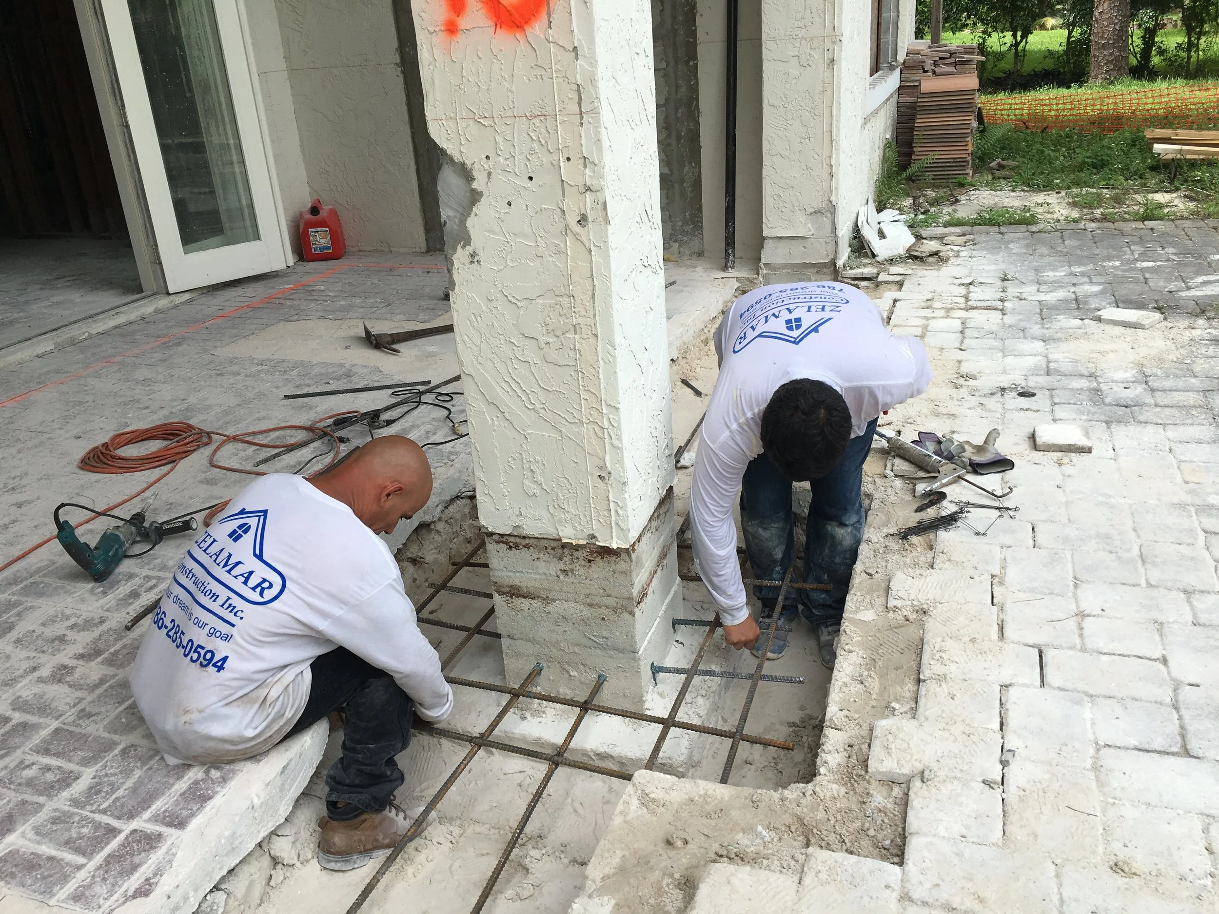 Dos trabajadores en construcción colocan armaduras de acero en el suelo, en un proyecto de cimentación de una estructura.