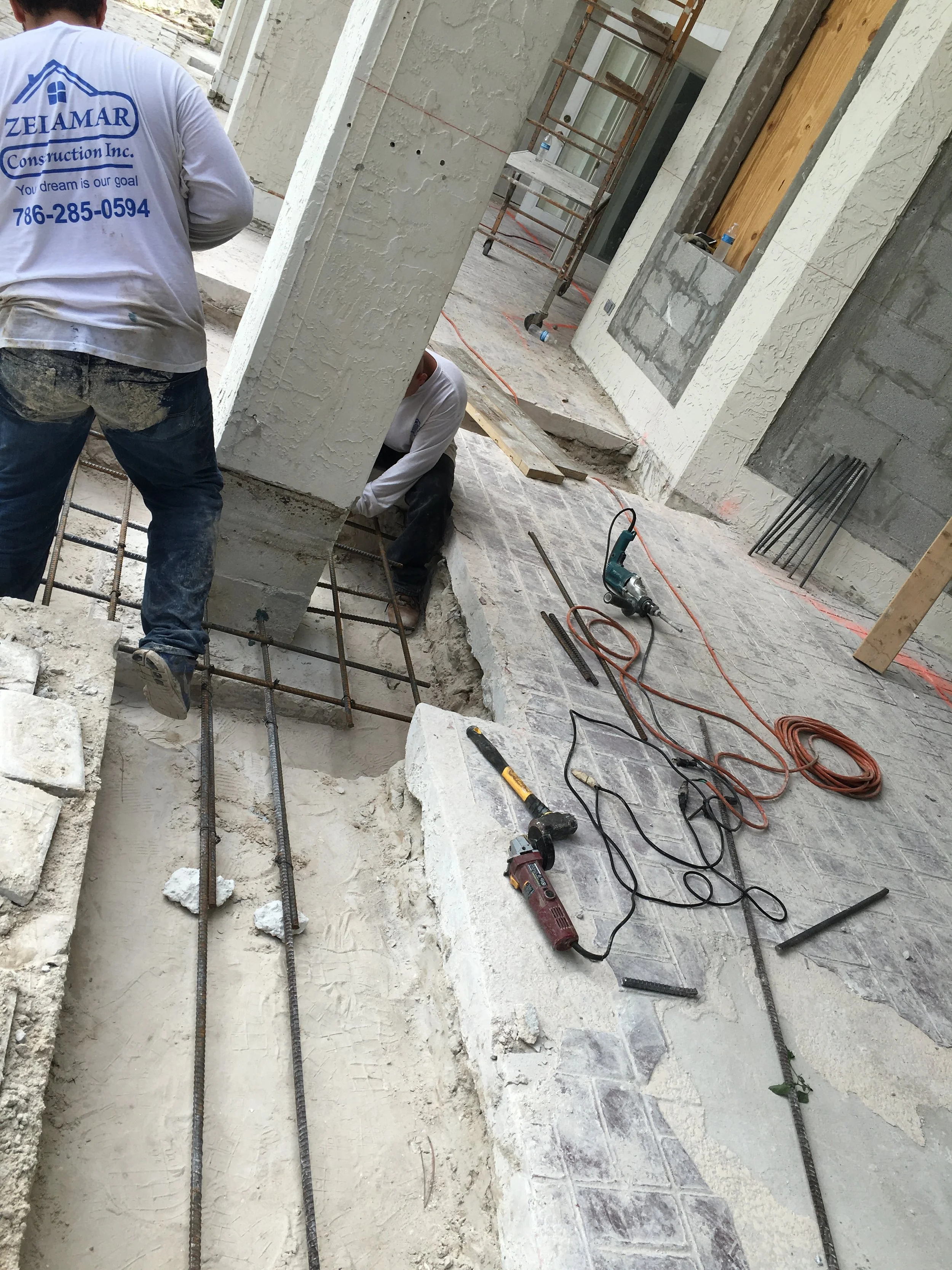 Trabajadores de construcción en obra levantando una columna con estructura de varillas de acero y cemento en un espacio interior