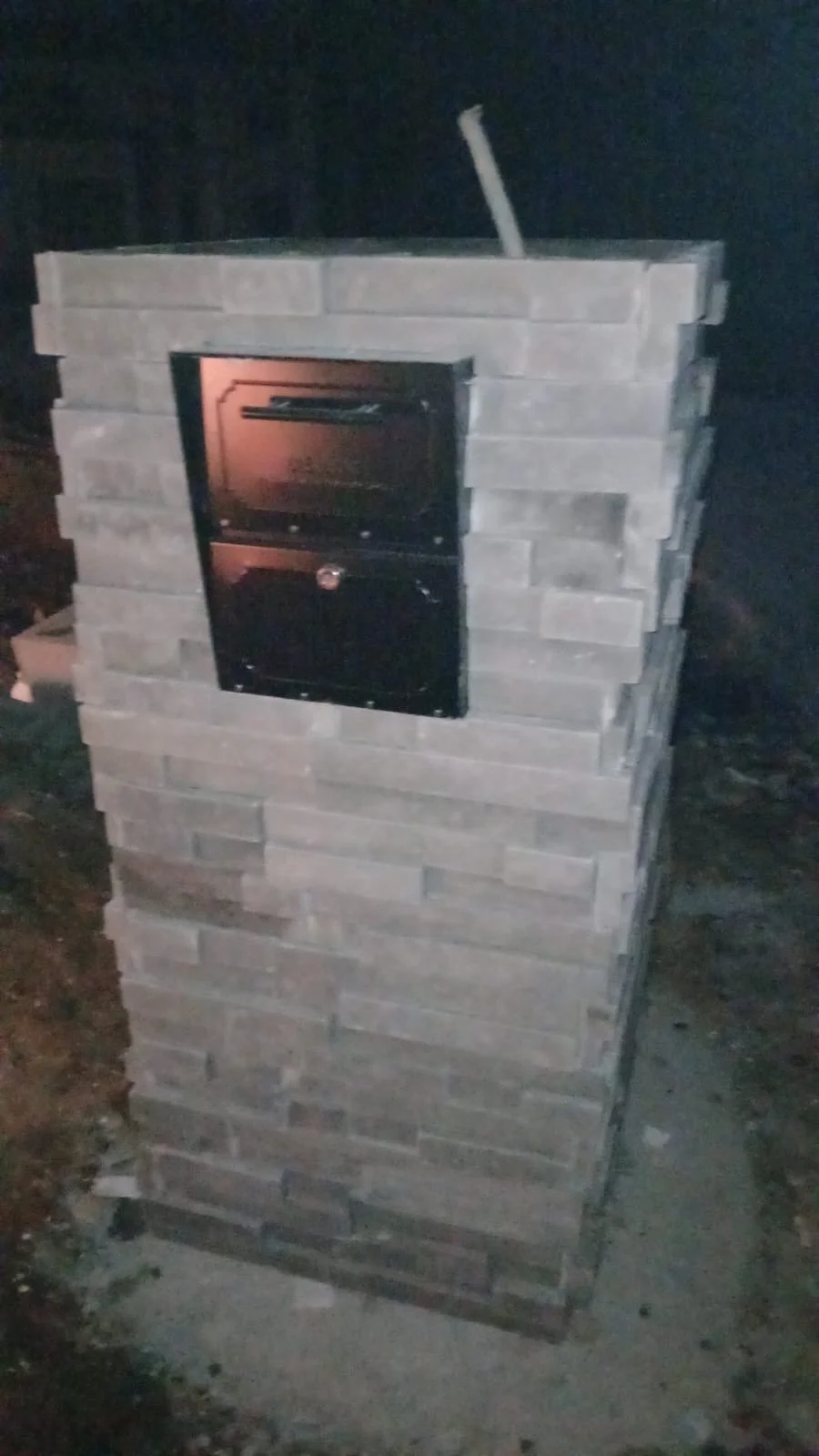 Horno de ladrillo con puerta de horno en la parte frontal, en un momento nocturno.