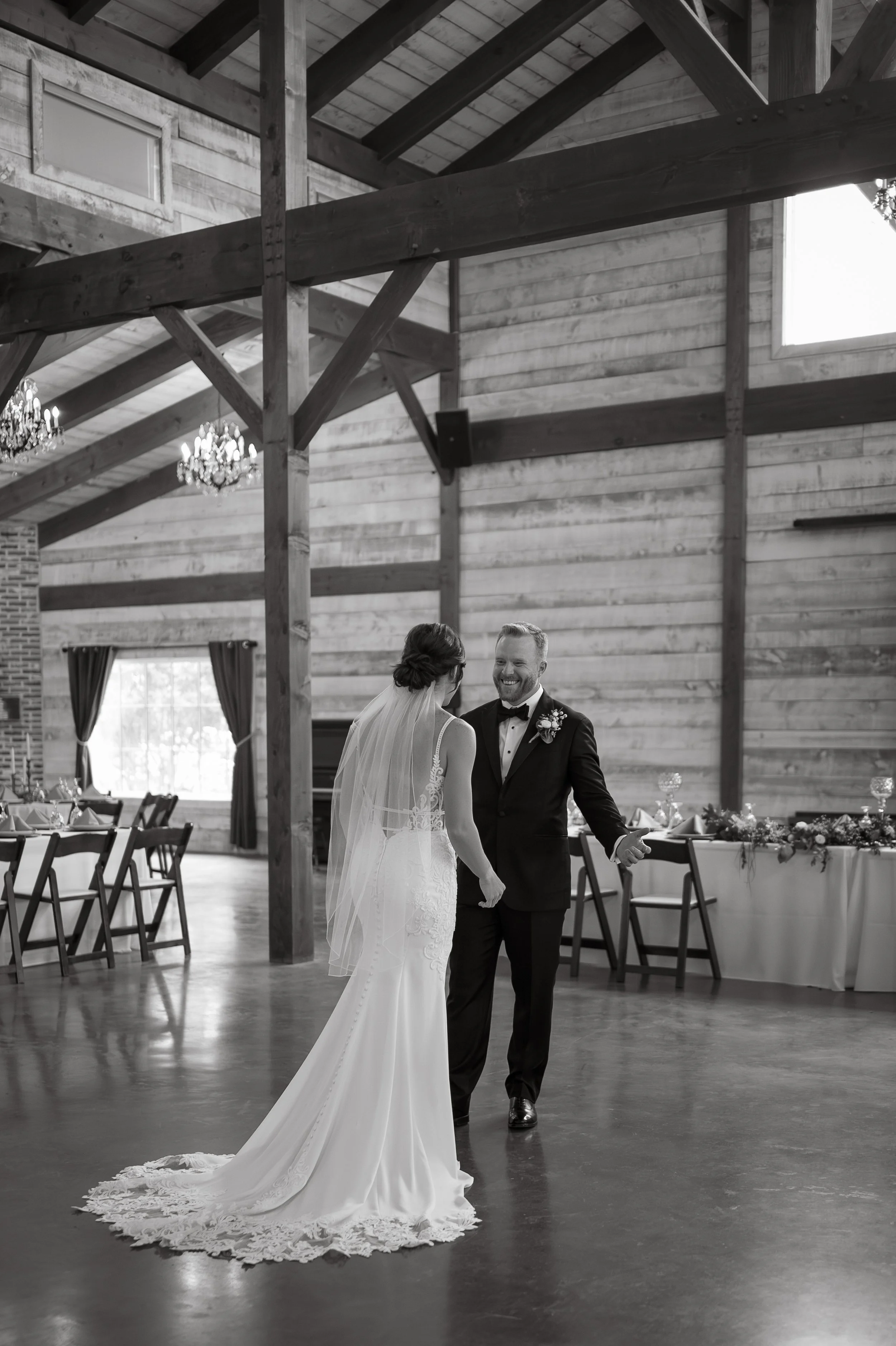A bride and groom share a dance in a rustic wooden barn decorated for a wedding reception.