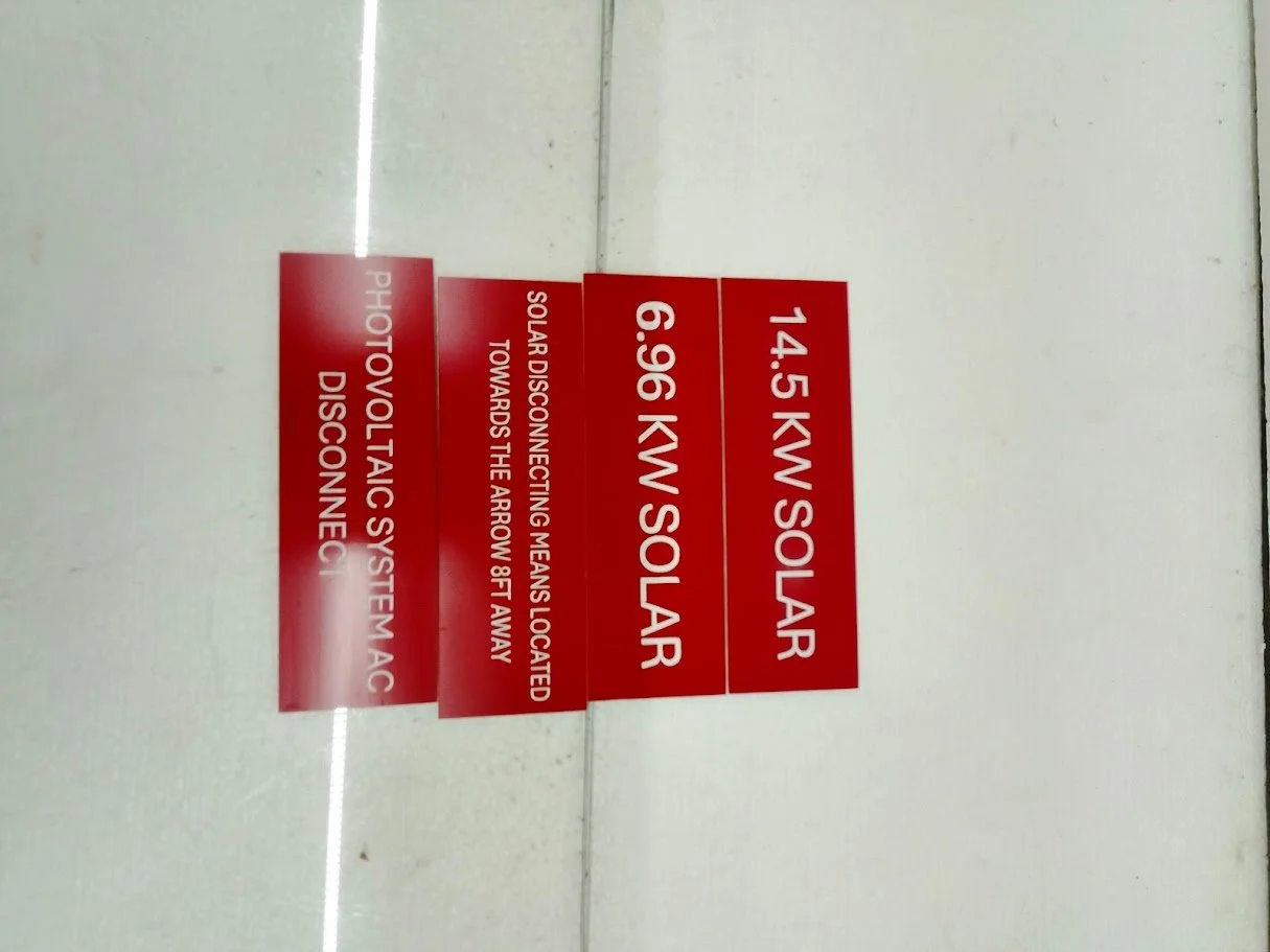 Red warning signs indicating a photovoltaic solar power system with 14.5 kilowatts and 6.96 kW inverters, and instructions for disconnection and remote disconnection.