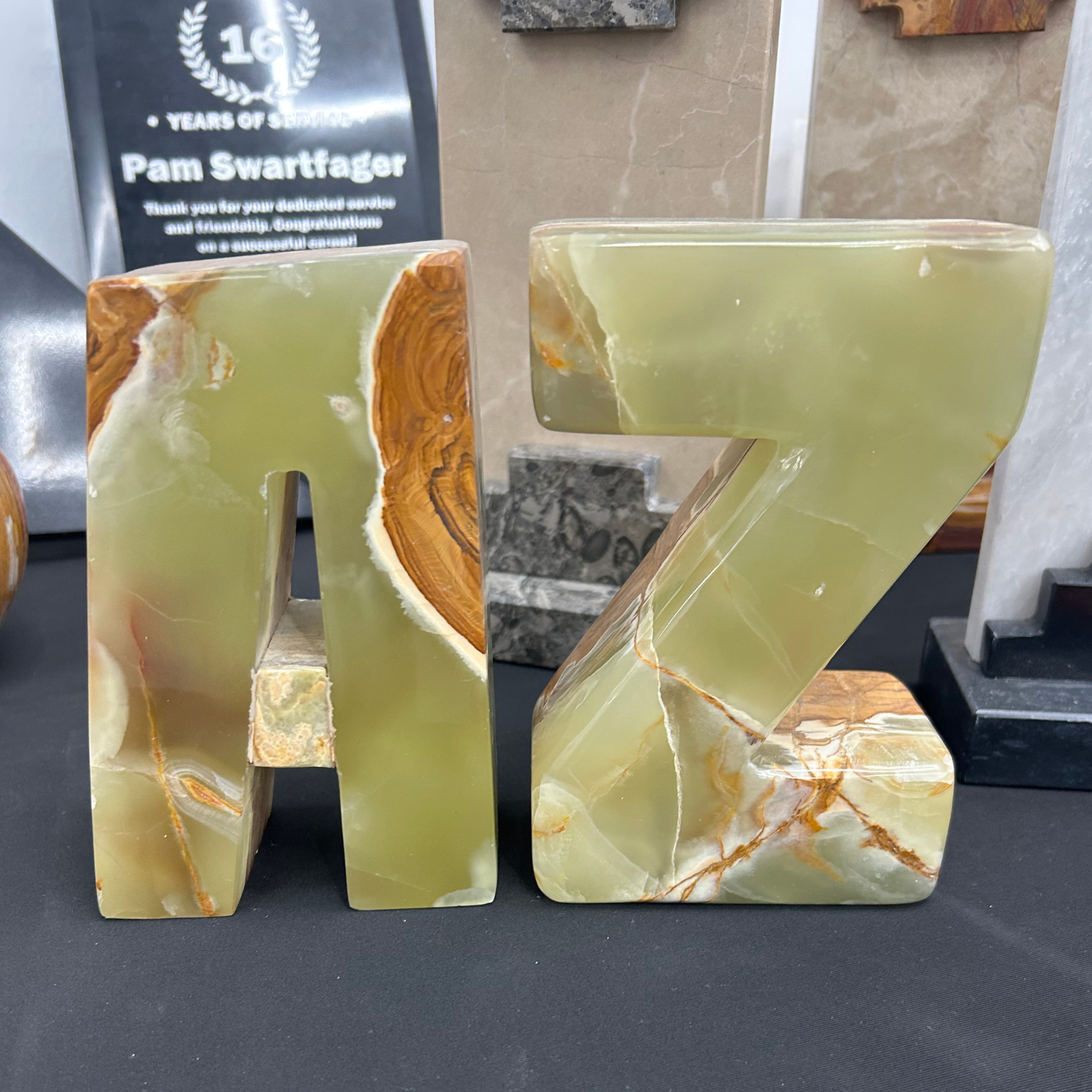 Close-up of marble or onyx decorative objects with green, orange, and white patterns on a black surface.