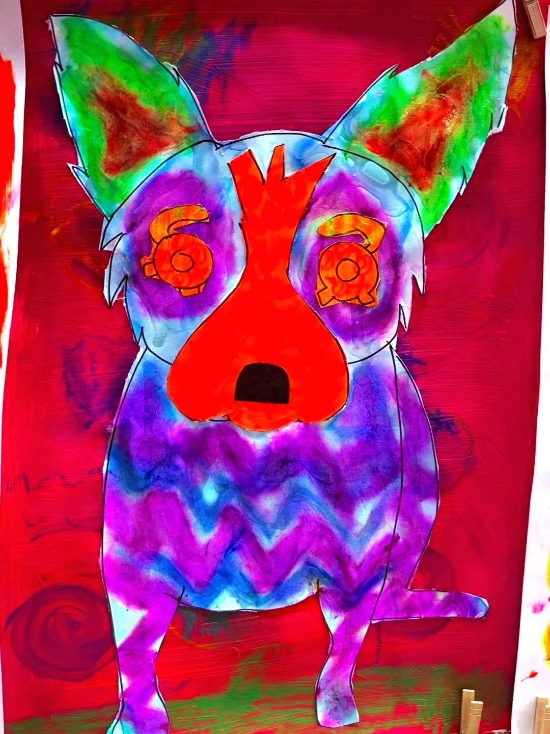A colorful abstract drawing of a dog with large ears, with dollar signs in its eyes, a red face, and a purple and blue body, set against a red background.