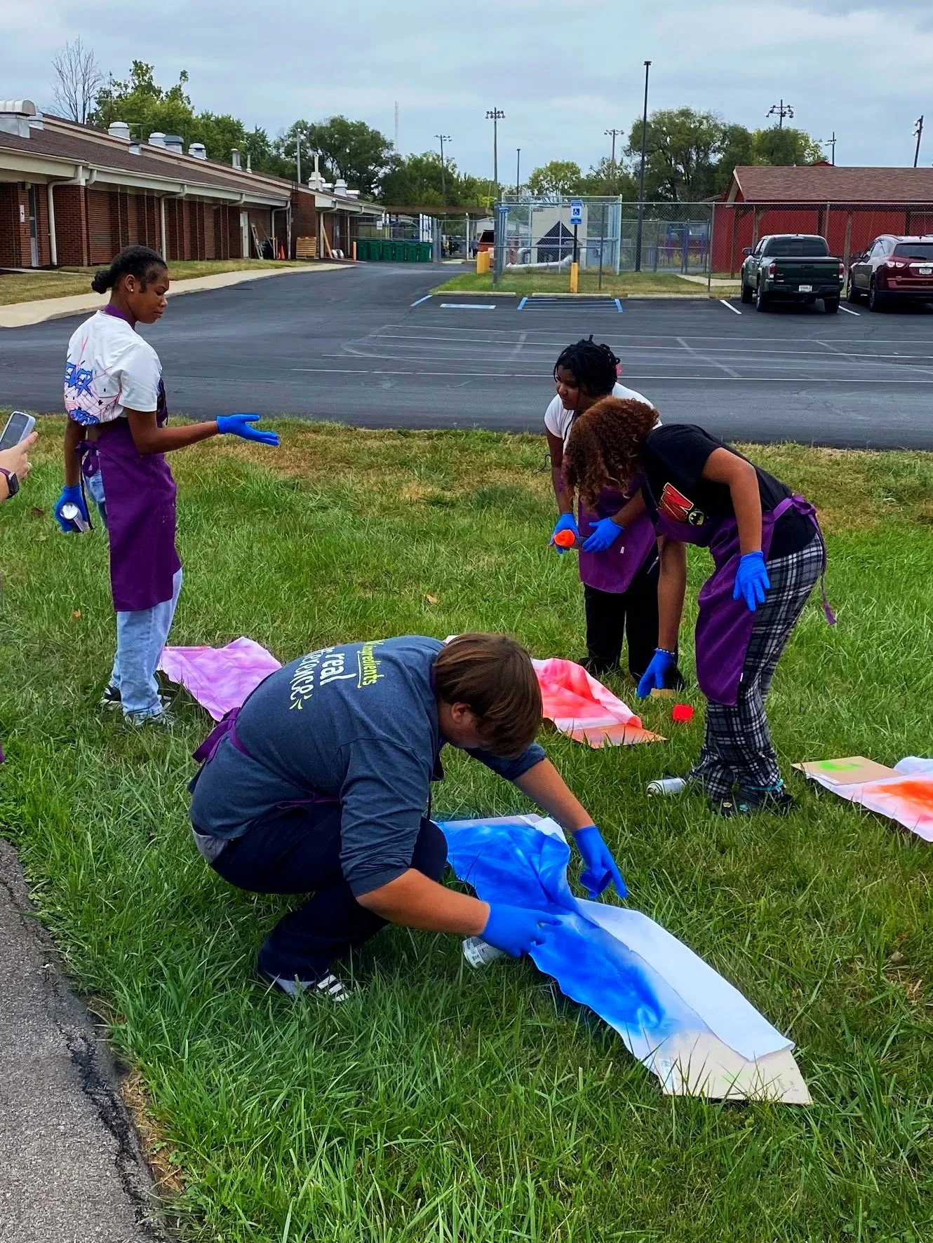 Group of people painting banners on the grass.