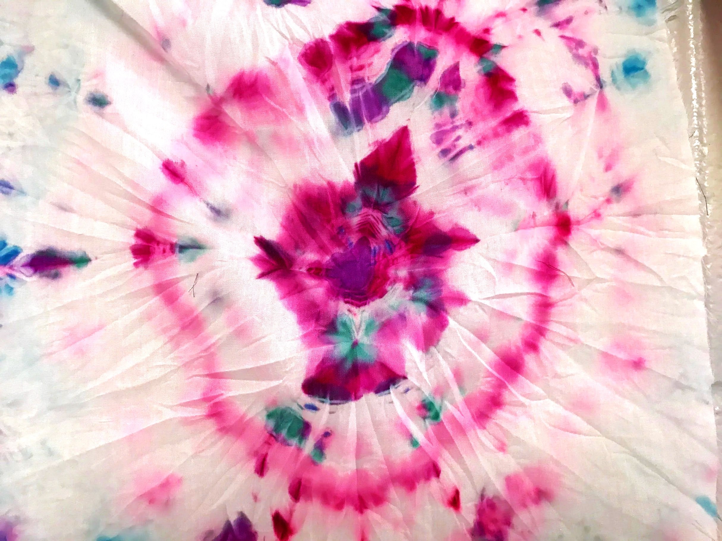 Colorful tie-dye fabric with pink, purple, green, and blue patterns.