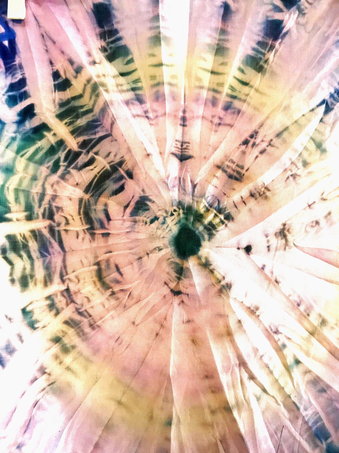 Close-up of a tie-dye created by a student with special needs. It has a green crown at the center, showing the detailed texture and pattern on the surface.