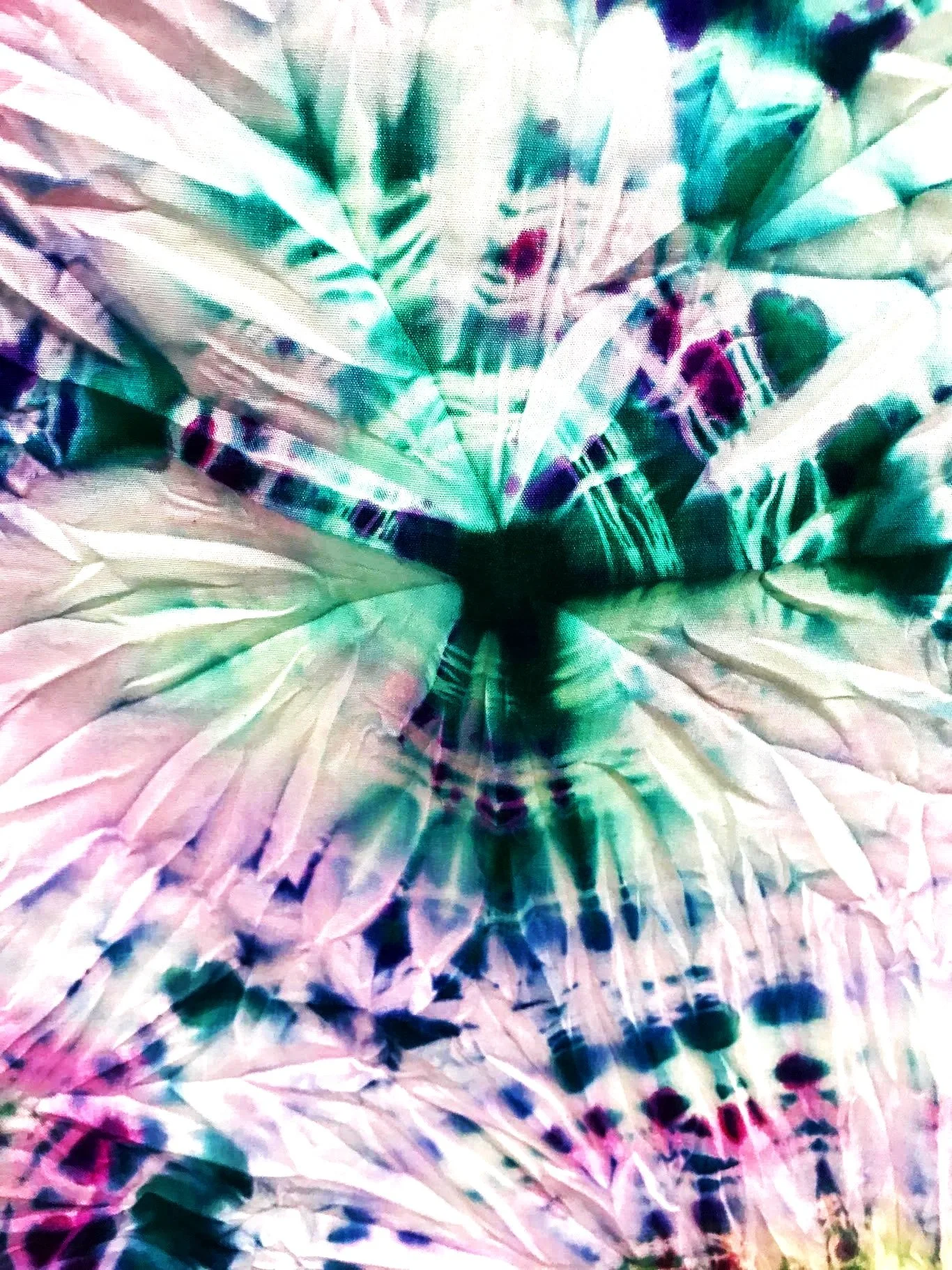 Colorful tie-dye pattern with a mix of green, blue, purple, pink, and white shades creating a vibrant abstract design.