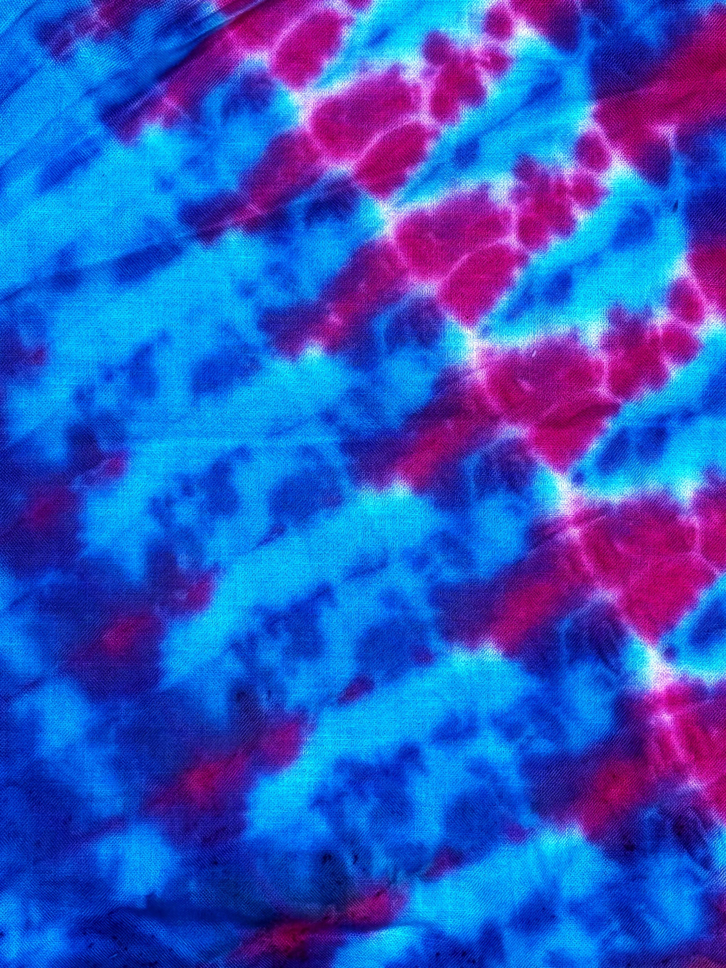 Close-up of a tie-dye fabric with vibrant blue, pink, and purple colors in a swirling pattern.