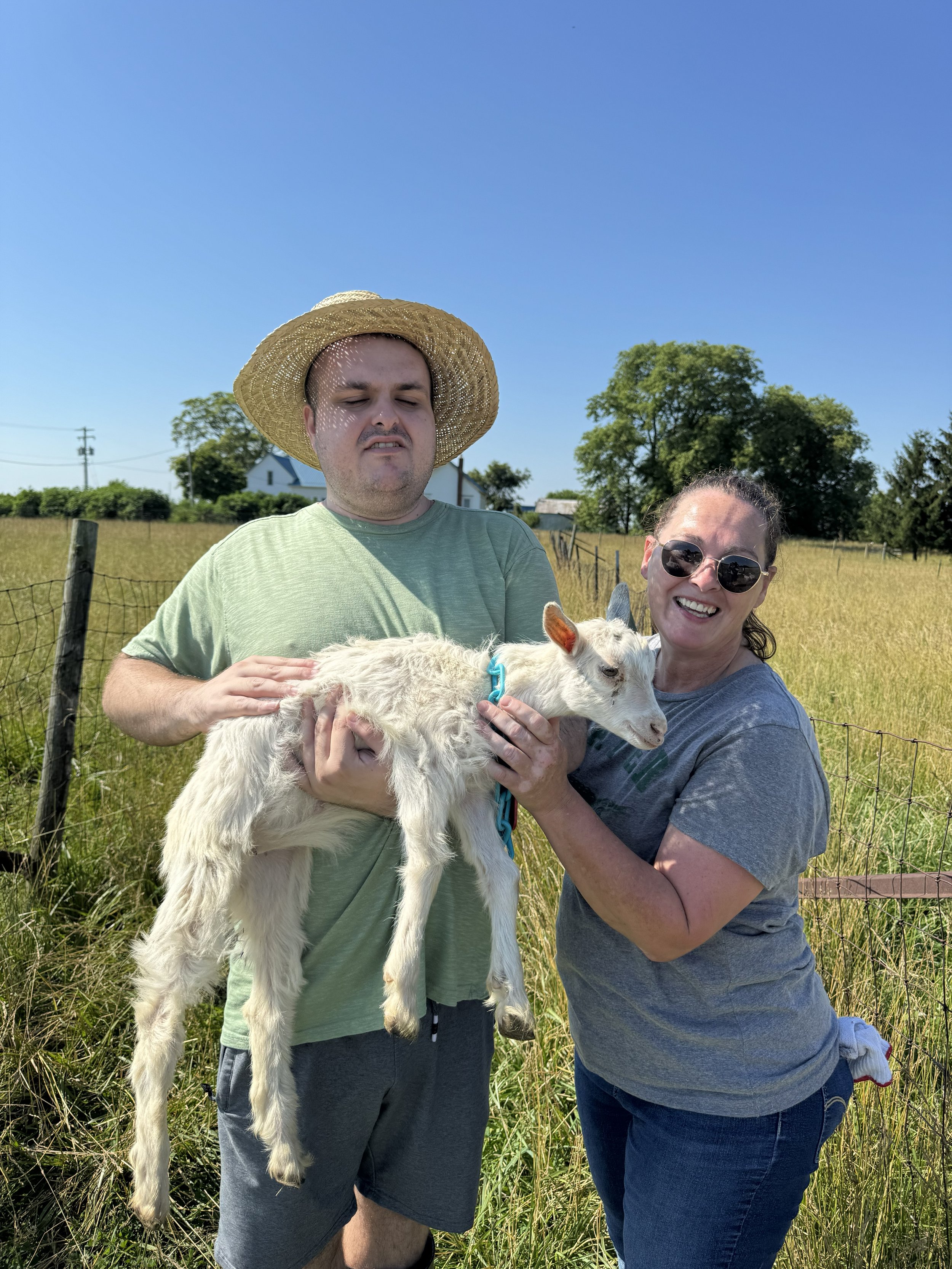 Amanda and Jack spending time with a goat during a hands-on farm experience
