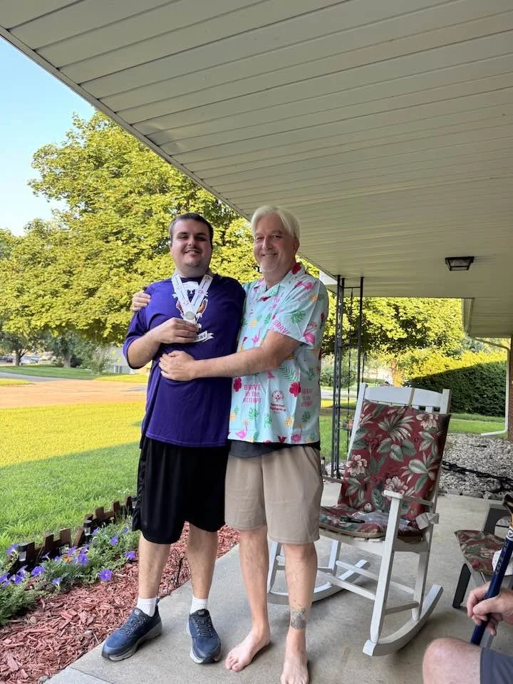 Jack and his father, Rich, hugging and smiling together on a porch on a beautiful day