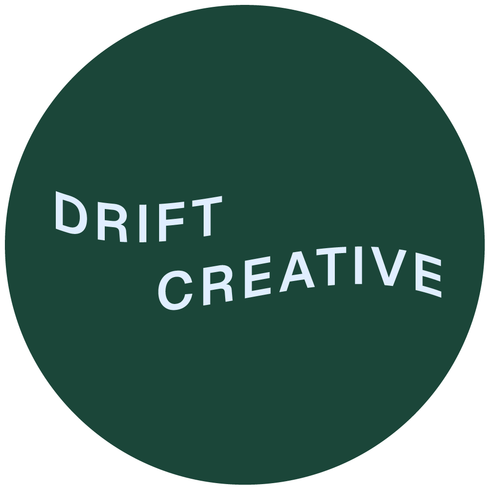 Circular logo with the words 'DRIFT CREATIVE' in light gray text on a dark green background, with 'DRIFT' curved upward and 'CREATIVE' curved downward.
