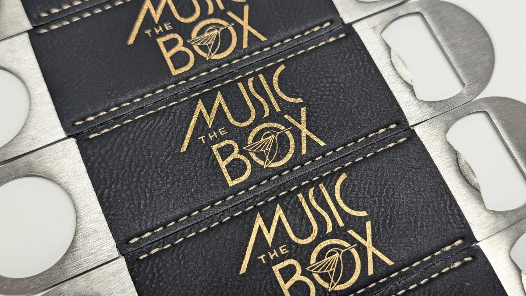 Custom leather bottle openers with engraved gold design
