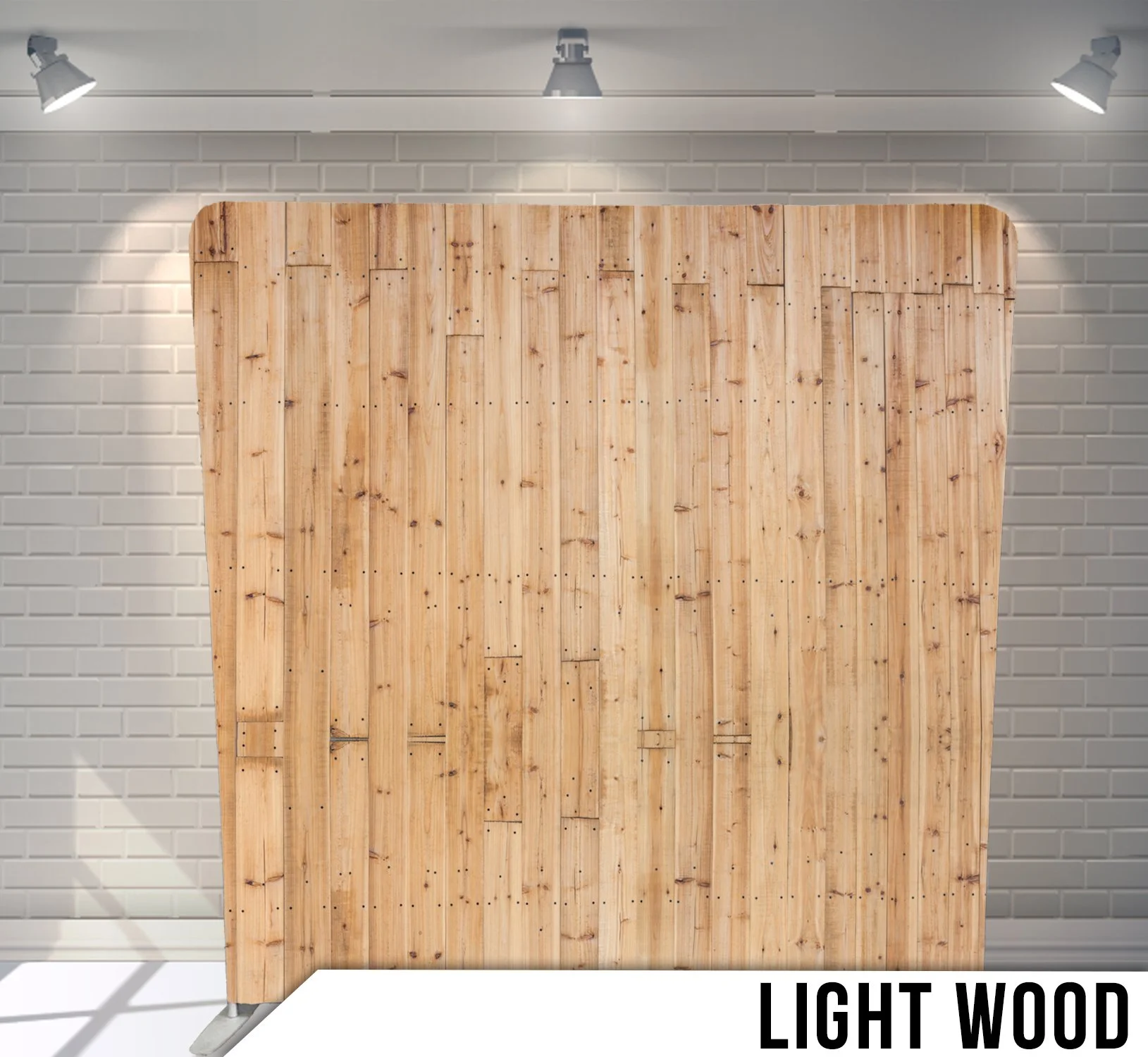 A light wood partition with a curved top, set against a white brick wall, lit by three adjustable ceiling lights.