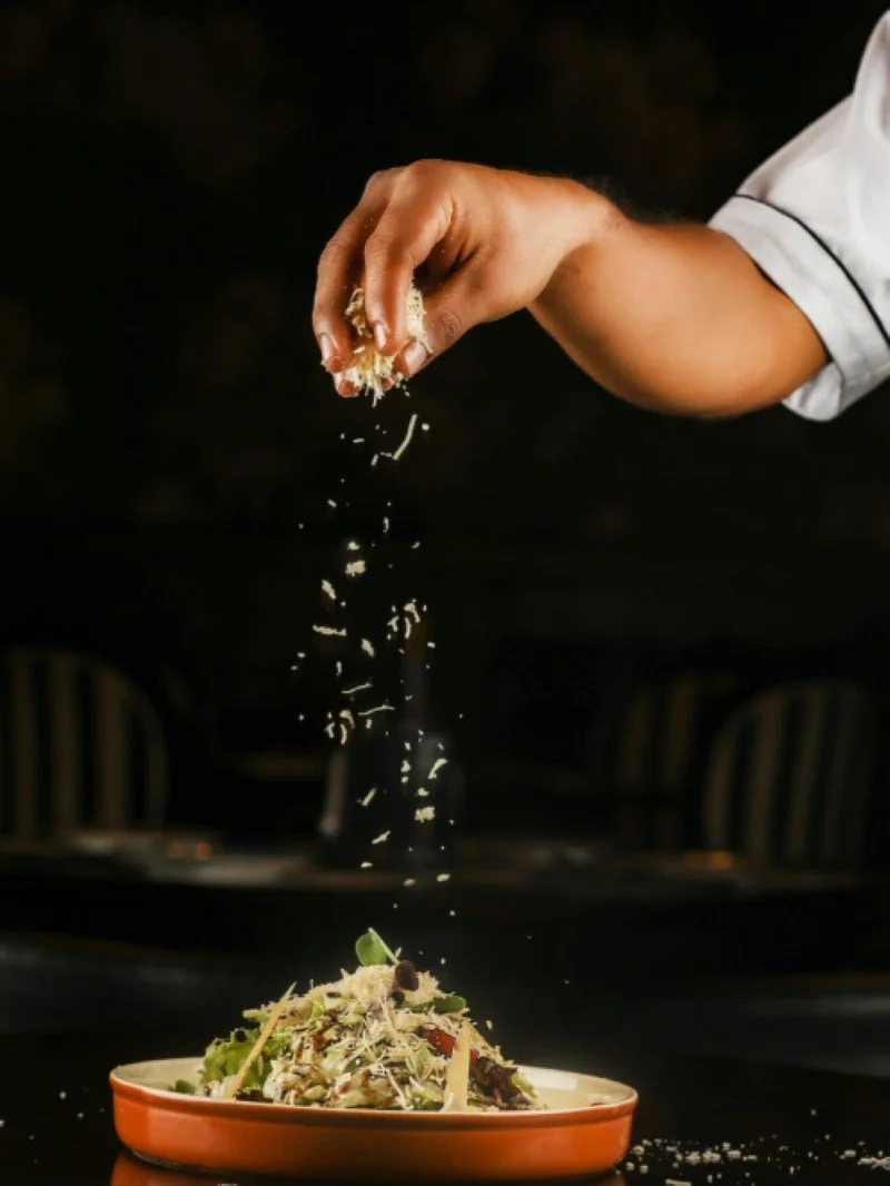 Chef plating and finishing a dish in a professional restaurant kitchen, representing operational food and beverage advisory.