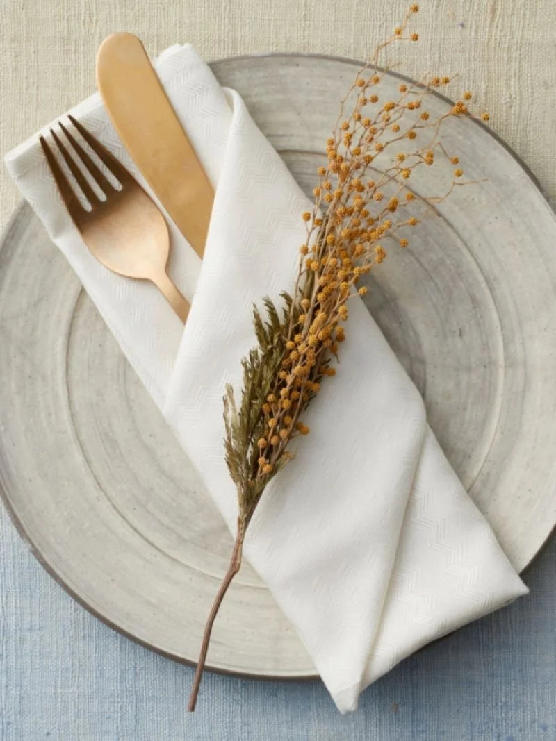 Hospitality concept strategy visual featuring refined table setting with ceramic plate, linen napkin, wooden cutlery, and natural styling.