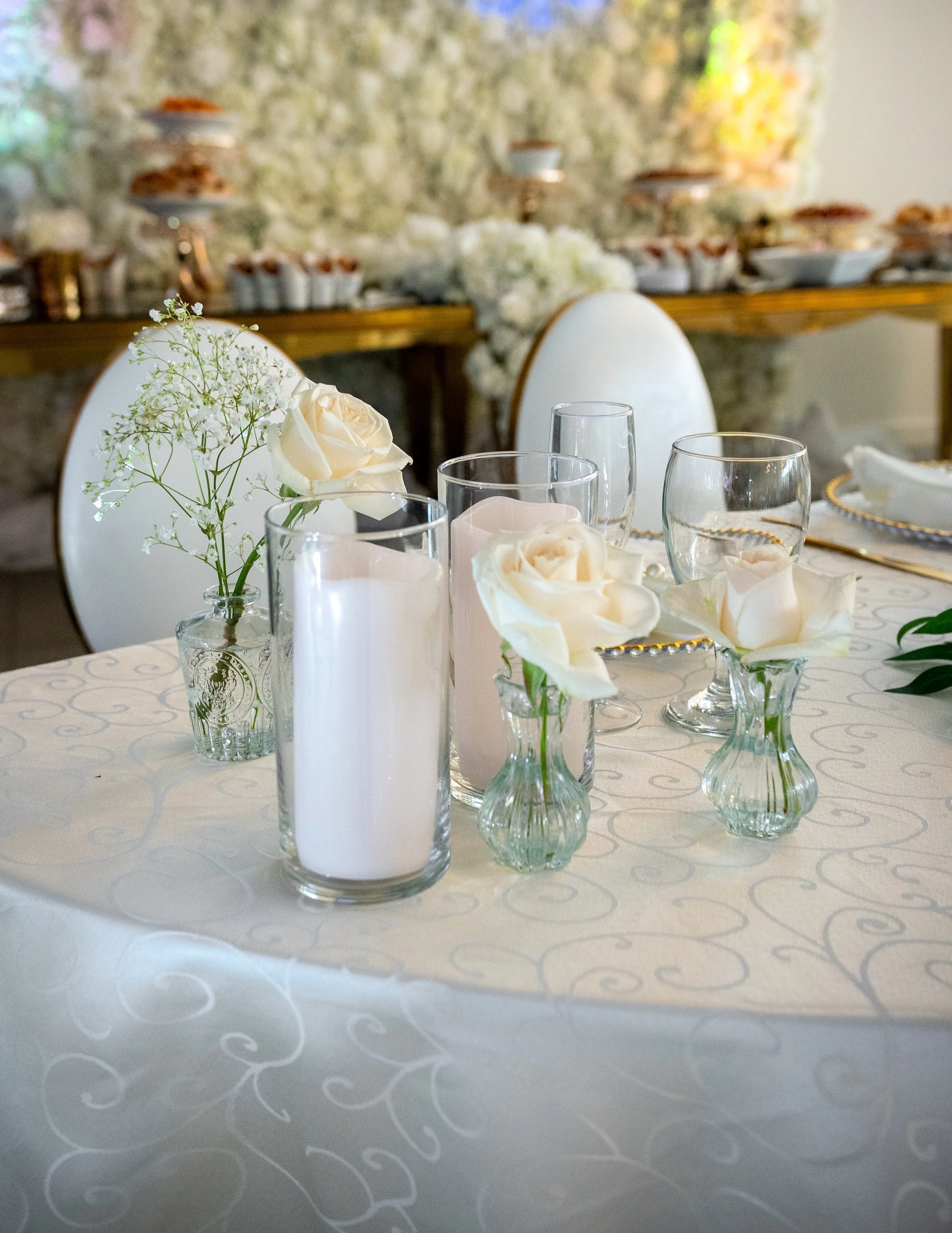 Table setting with white roses and candles, decorated for a wedding or elegant event.