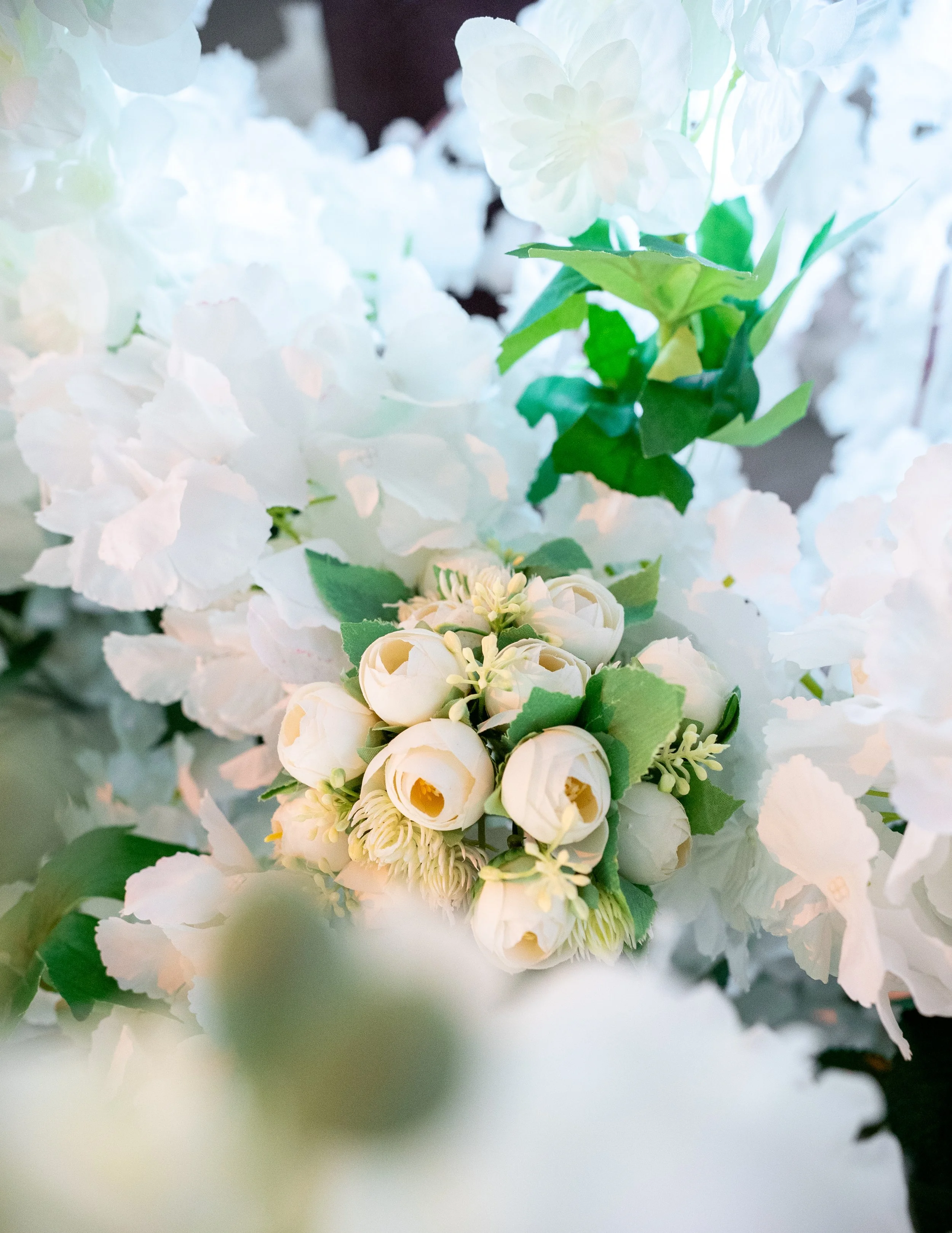 Close-up of white flowers including hydrangeas, roses, and other blooms with green leaves.