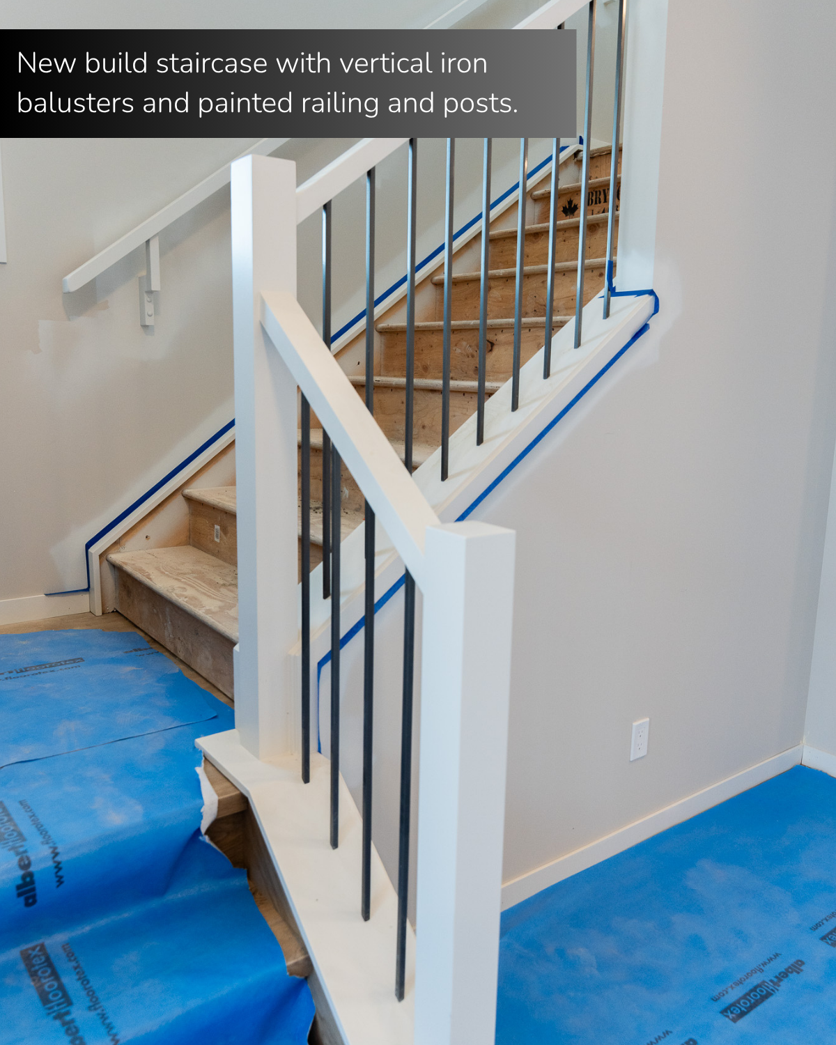 New build staircase with vertical iron balusters and painted railing and posts. 