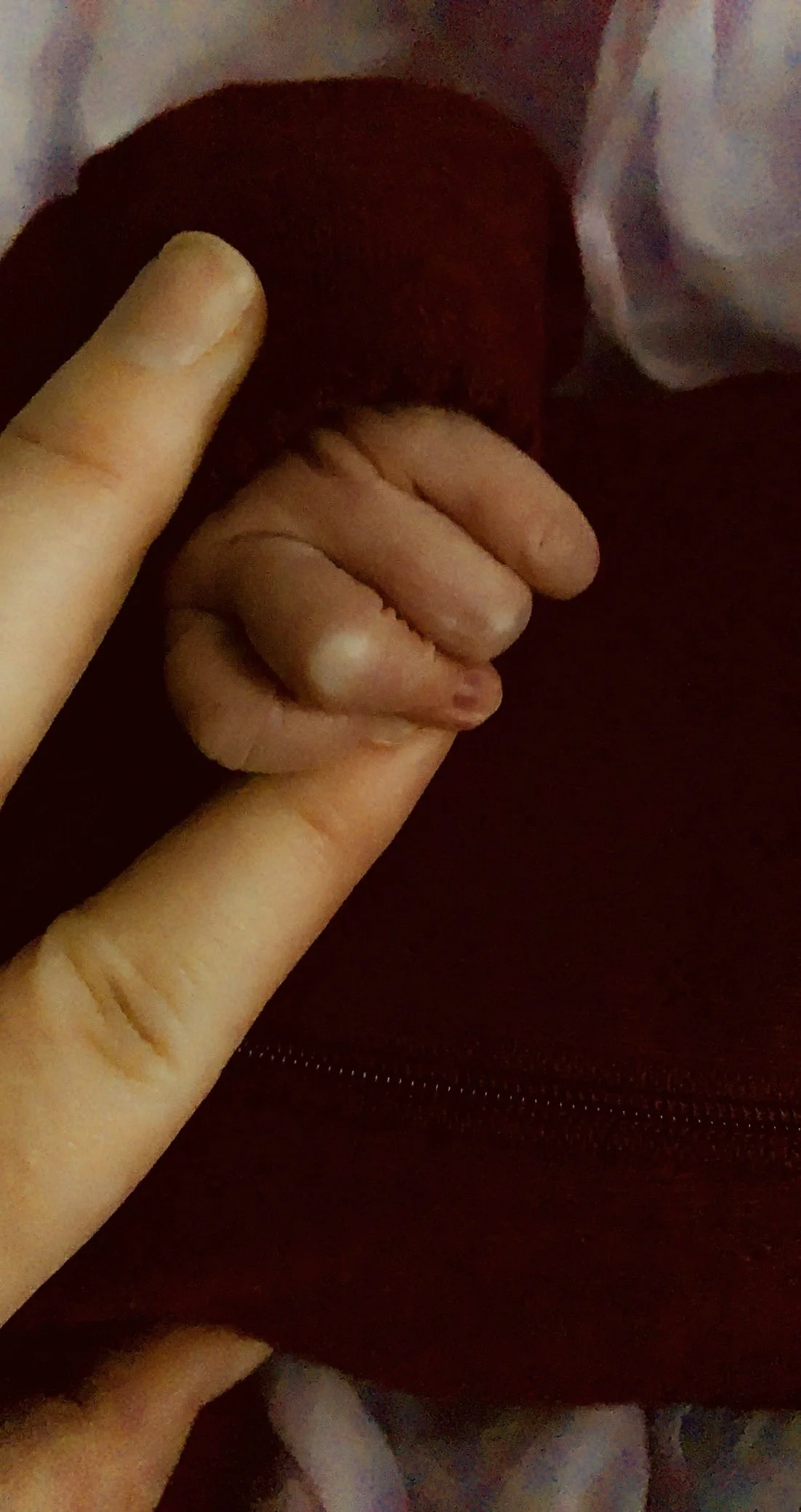 A close-up image of a hand with fingers making a peace sign, resting on what appears to be a person's leg or clothing.